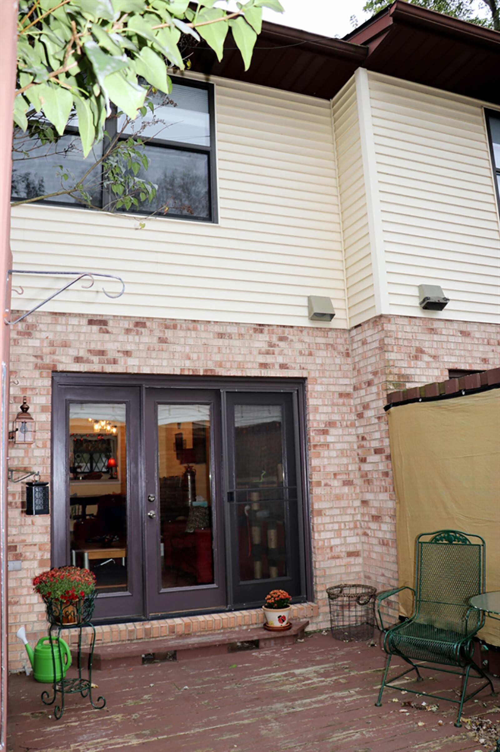 Triple-panel patio doors fill the combined area with natural light and offer a view of the private rear deck. A wooden privacy fence surrounds the wooden deck, creating the courtyard setting. A gate opens into an alley garden area where gardens flank a walkway to the rear parking area. CONTRIBUTED PHOTO BY KATHY TYLER