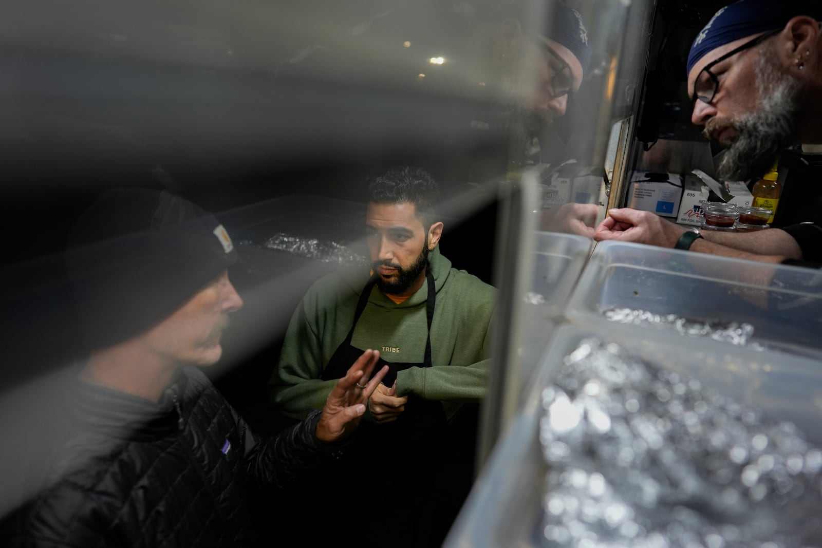 World Central Kitchen Chef Corp member Daniel Shemtob, center, and Benton Atkisson, right, serve Eaton Fire first responders from Shemtob's food truck, The Lime Truck, at the Rose Bowl Stadium, Wednesday, Jan. 15, 2025, in Pasadena, Calif. (AP Photo/Carolyn Kaster)