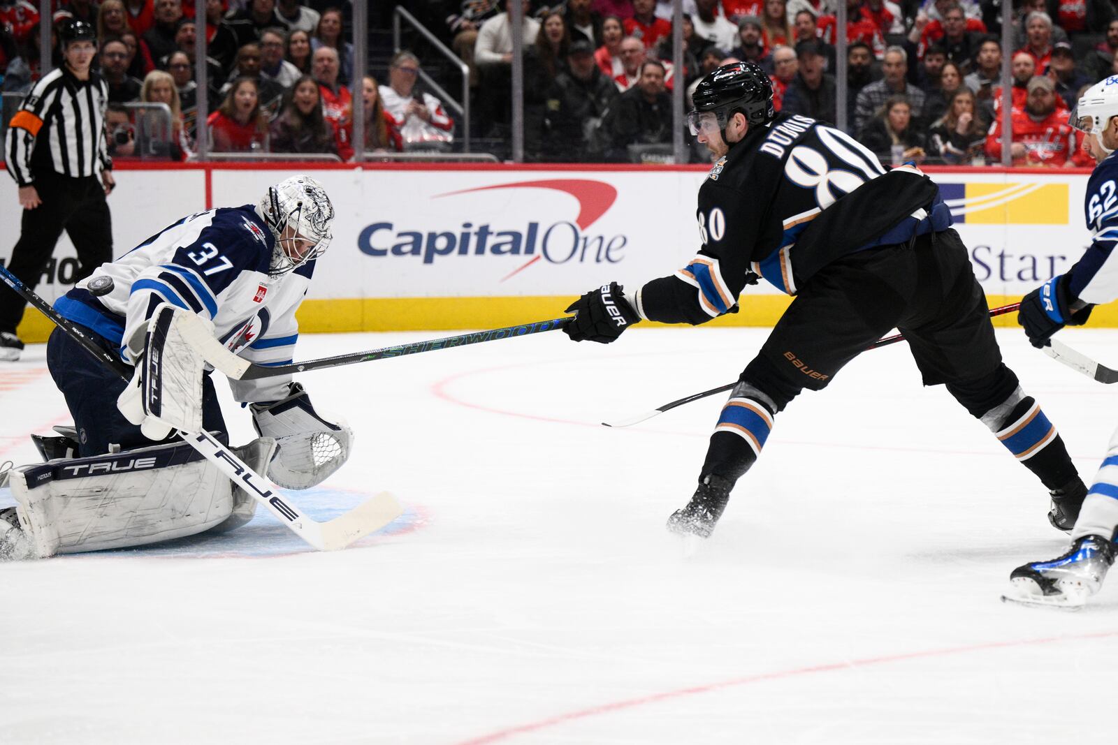 Washington Capitals left wing Pierre-Luc Dubois (80) tries to get the puck past Winnipeg Jets goaltender Connor Hellebuyck (37) during the first period of an NHL hockey game, Saturday, Feb. 1, 2025, in Washington. (AP Photo/Nick Wass)