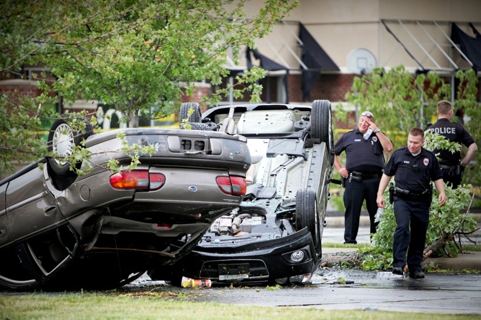 Tuesday’s tornado toppled vehicles, including these two, in the parking lot at the Greene Crossing Shopping Center on Indian Ripple Road. (Jim Noelker/Staff)