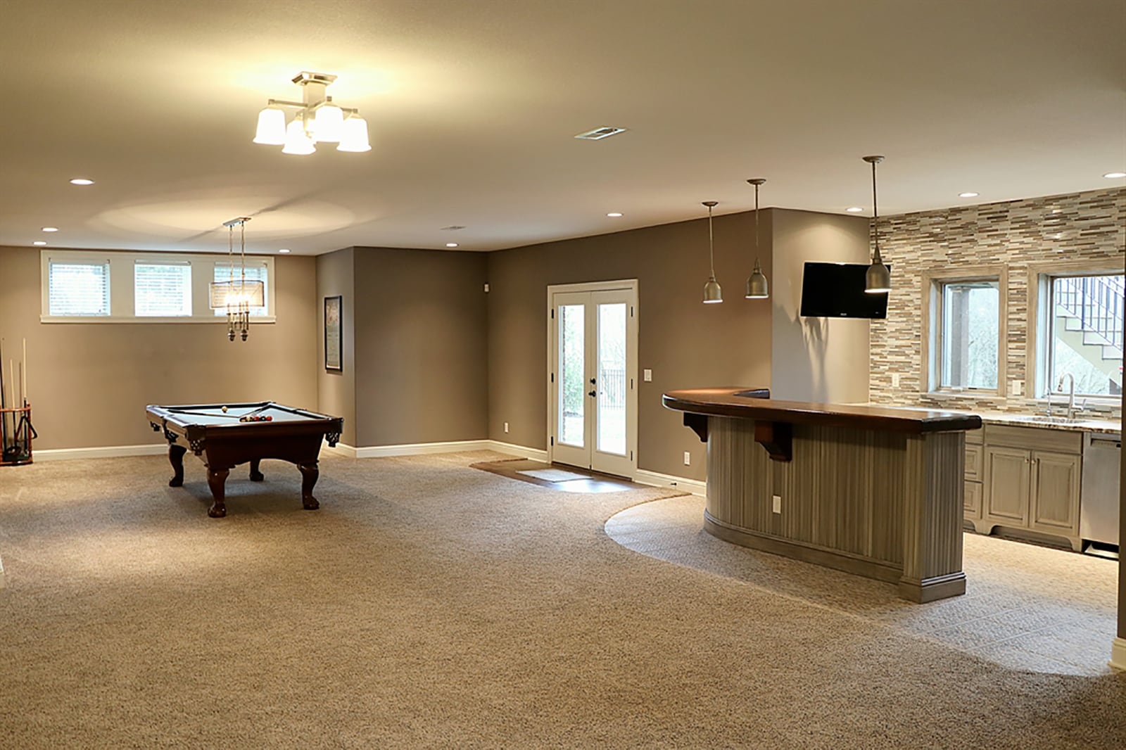 The lower level has been completely finished with a large recreation and family room at the bottom of the open stairwell. Nestled under the staircase is a kitchenette with a wall of windows above a granite countertop. A peninsula bar has a hand-carved wood counter and bead-board wrap. CONTRIBUTED PHOTO BY KATHY TYLER