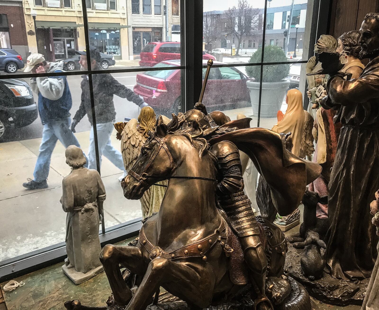 People walk by the front window of the Dayton Church Supply on East Third St. and find hundreds of religious statues staring back through the window.