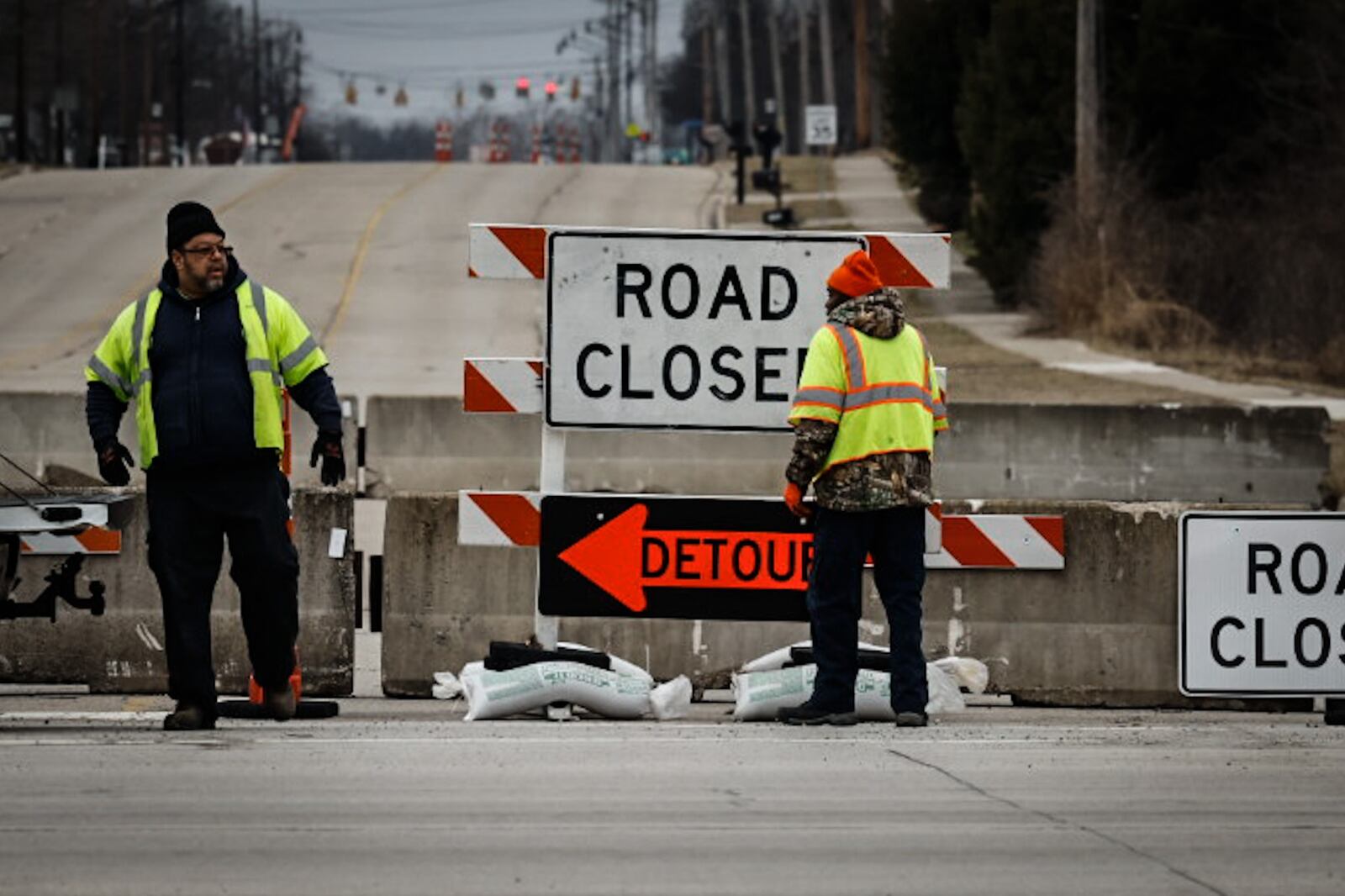 Workers set more sandbags on the road closed signs at Ohio 49 and East Main Street Friday February 10, 2023. The bridge over Dry Run is going to be repaired because of erosion. JIM NOELKER/STAFF