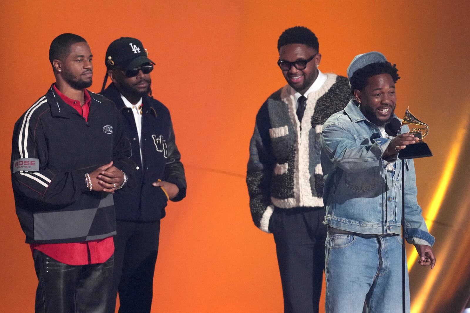 Kendrick Lamar, center, accepts the award for song of the year for "Not Like Us" during the 67th annual Grammy Awards on Sunday, Feb. 2, 2025, in Los Angeles. Dave Free, from left, Sounwave, and Mustard look on from rear of the stage.(AP Photo/Chris Pizzello)