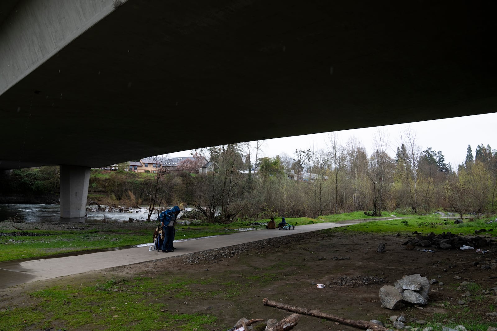 FILE - A homeless person adjusts the jacket after receiving it from another under Redwood Highway near Baker Park, March 22, 2024, in Grants Pass, Ore. (AP Photo/Jenny Kane, File)