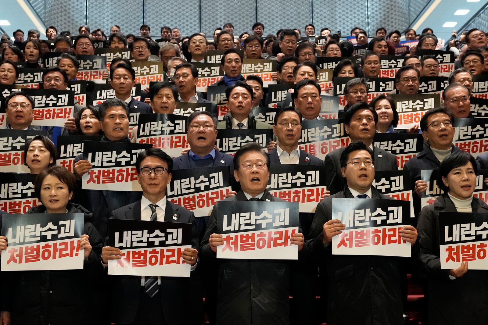 South Korea's main opposition Democratic Party leader Lee Jae-myung, bottom center, shout slogans during a press conference with his party members at the National Assembly in Seoul, South Korea, Saturday, Dec. 7, 2024. The signs read "Punish the rebellion leader." (AP Photo/Ahn Young-joon)