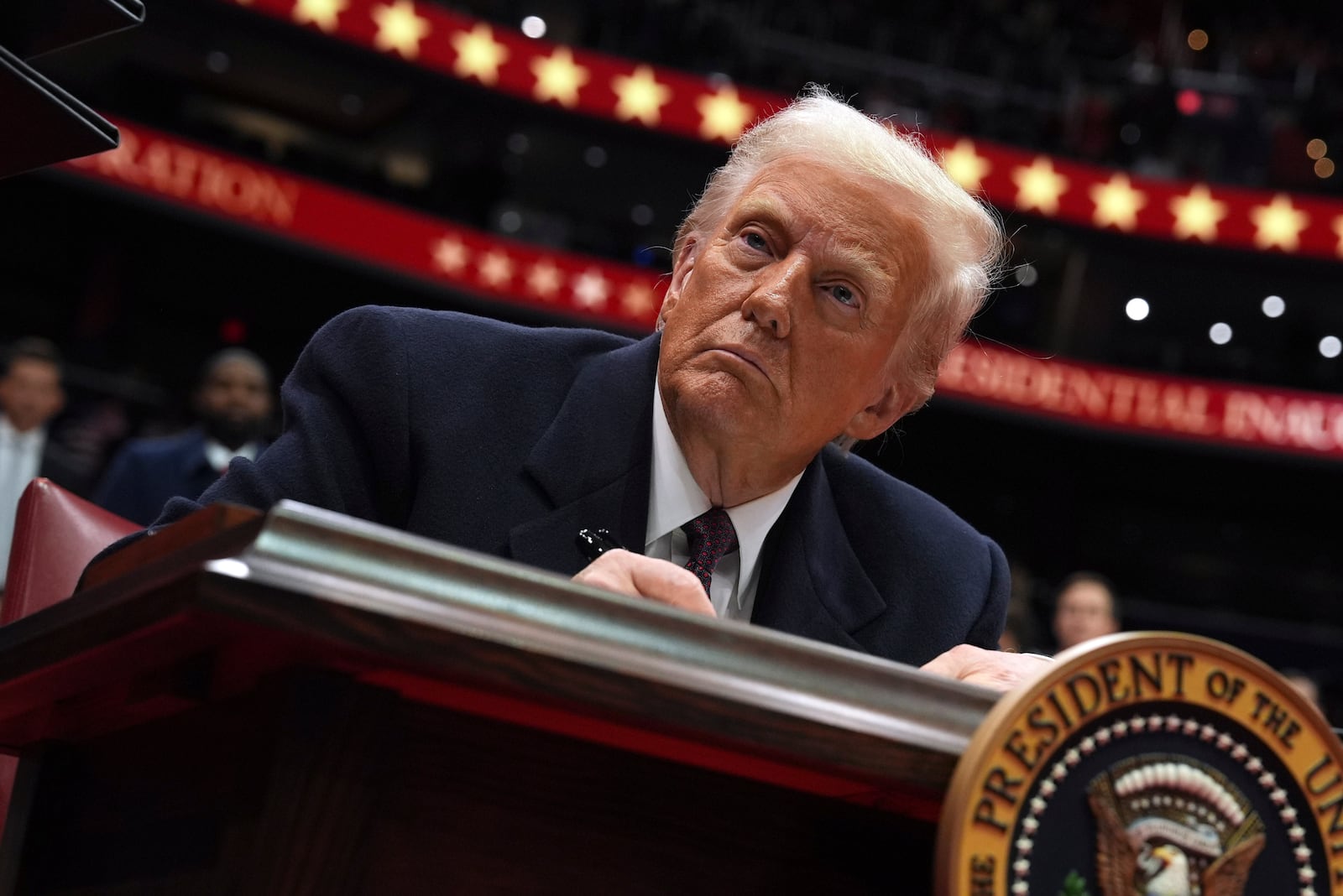 President Donald Trump signs an executive order as he attends an indoor Presidential Inauguration parade event at Capital One Arena, Monday, Jan. 20, 2025, in Washington. (AP Photo/Evan Vucci)