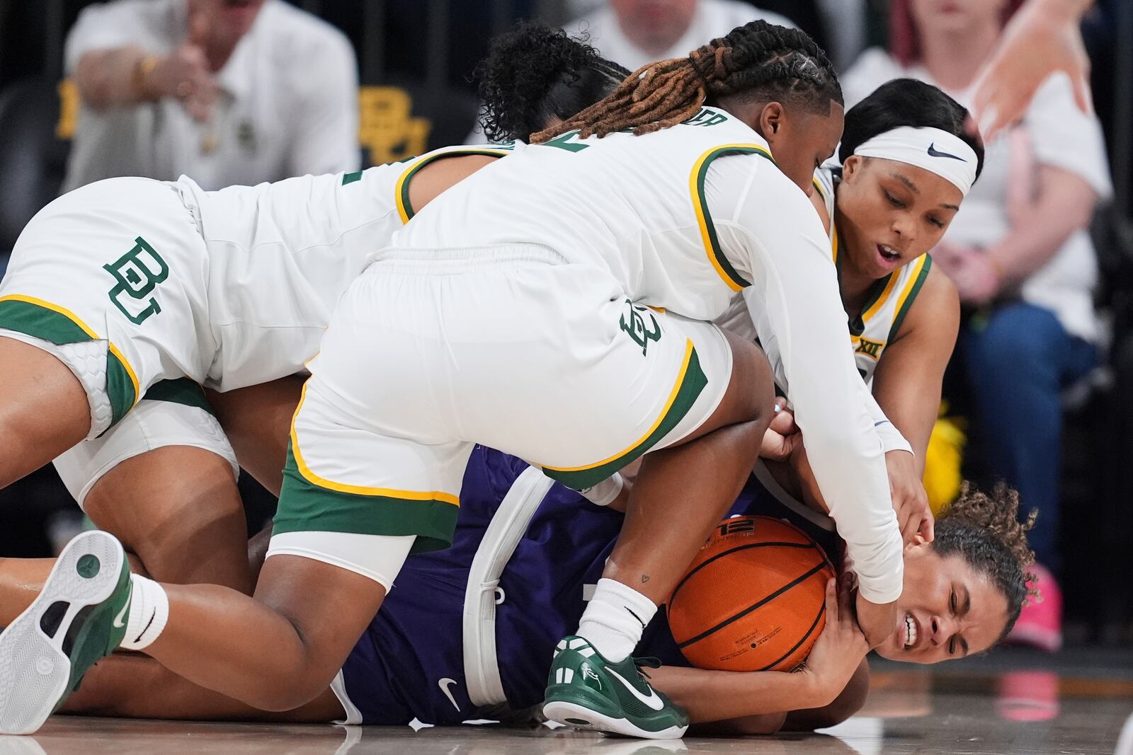 TCU guard Donovyn Hunter, bottom, holds onto the ball as Baylor's Yaya Felder, front, Bella Fontleroy, left, and Sarah Andrews, top right, wrestle on the floor for control in the first half of an NCAA college basketball game in Waco, Texas, Sunday, March 2, 2025. (AP Photo/Tony Gutierrez)