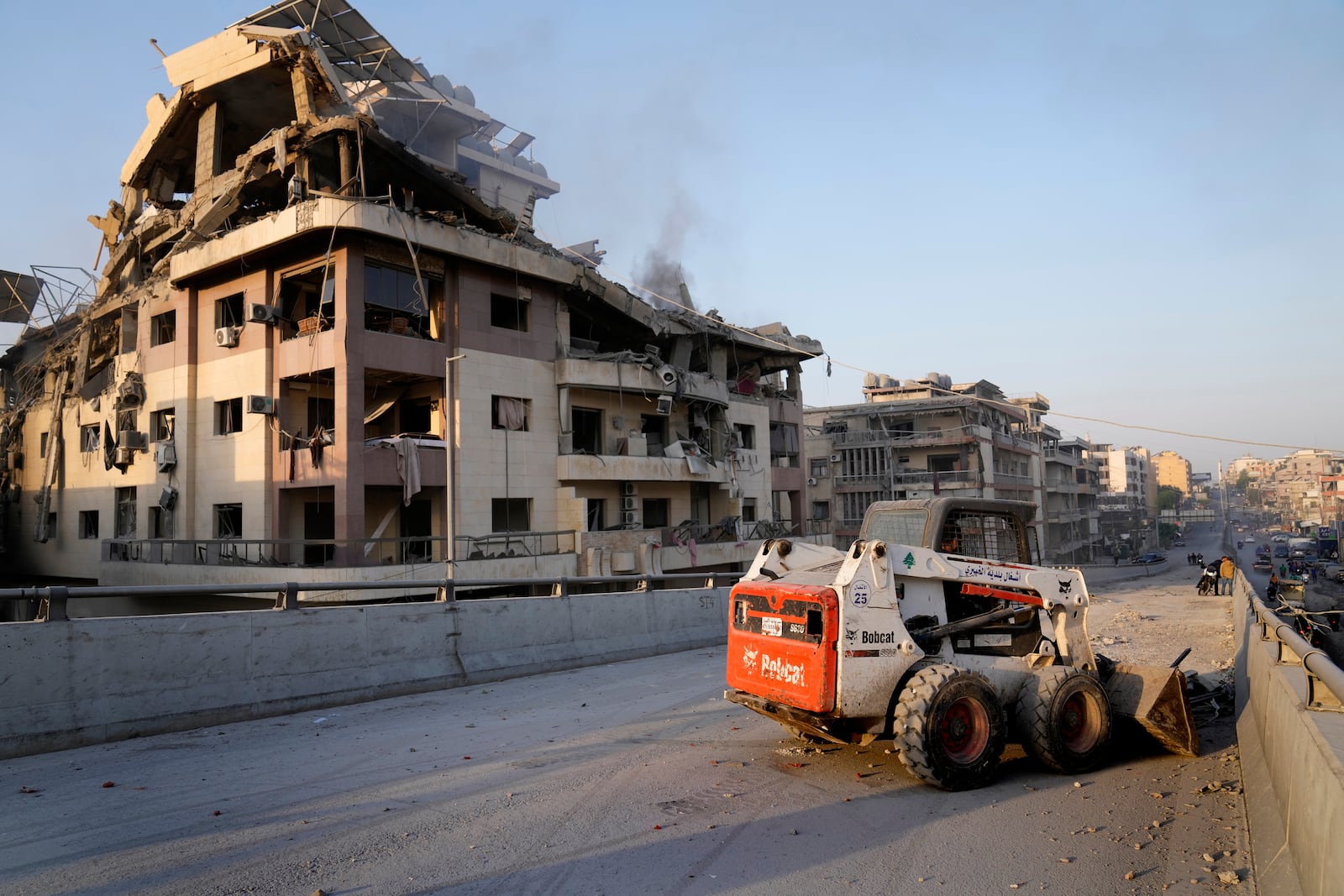 A municipality worker uses a skid steer loader to reopen a bridge closed by the rubble of a destroyed building that was hit by an Israeli airstrike on Dahiyeh, in the southern suburb of Beirut, Lebanon, Friday, Nov. 1, 2024. (AP Photo/Hussein Malla)