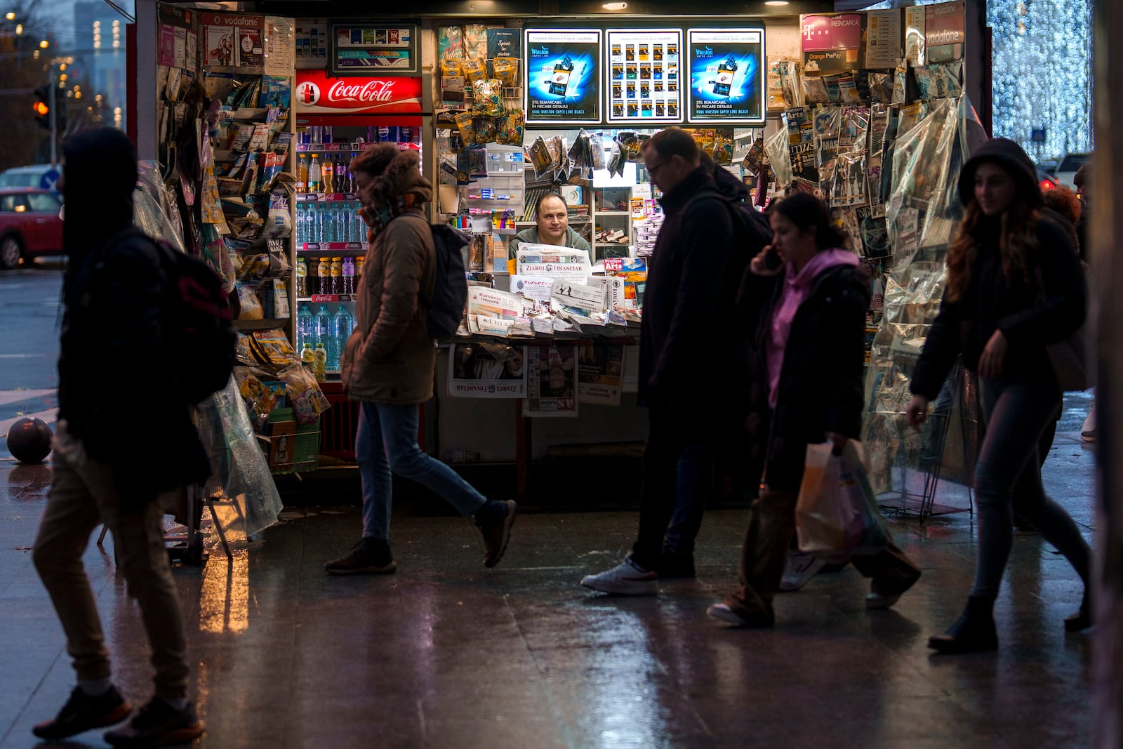 People walk by a newspaper stand after the Constitutional Court annulled the first round of the country's presidential election, days after allegations that Russia ran a coordinated online campaign to promote Calin Georgescu a far-right outsider who won the first round, in Bucharest, Romania, Friday, Dec. 6, 2024. (AP Photo/Vadim Ghirda)