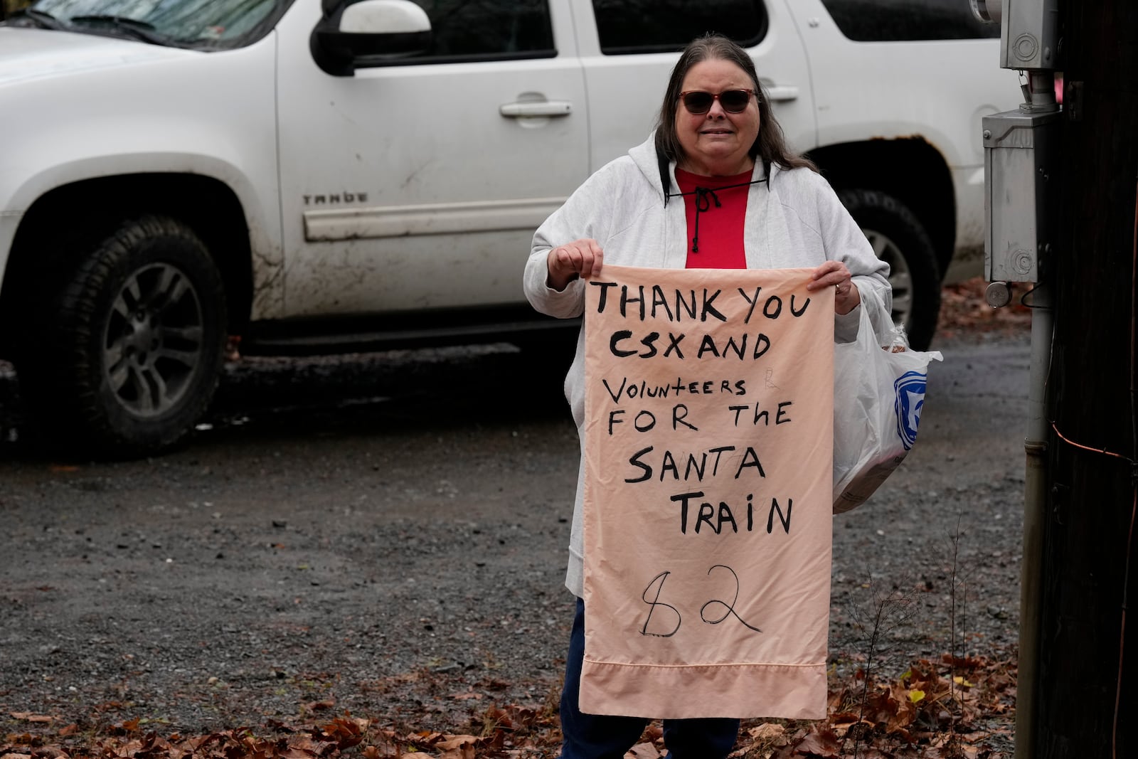 Sandra Owens holds a sign thanking volunteers during the 82nd run of the CSX Santa Train, Saturday, Nov. 23, 2024, in Haysi, Va. (AP Photo/George Walker IV)