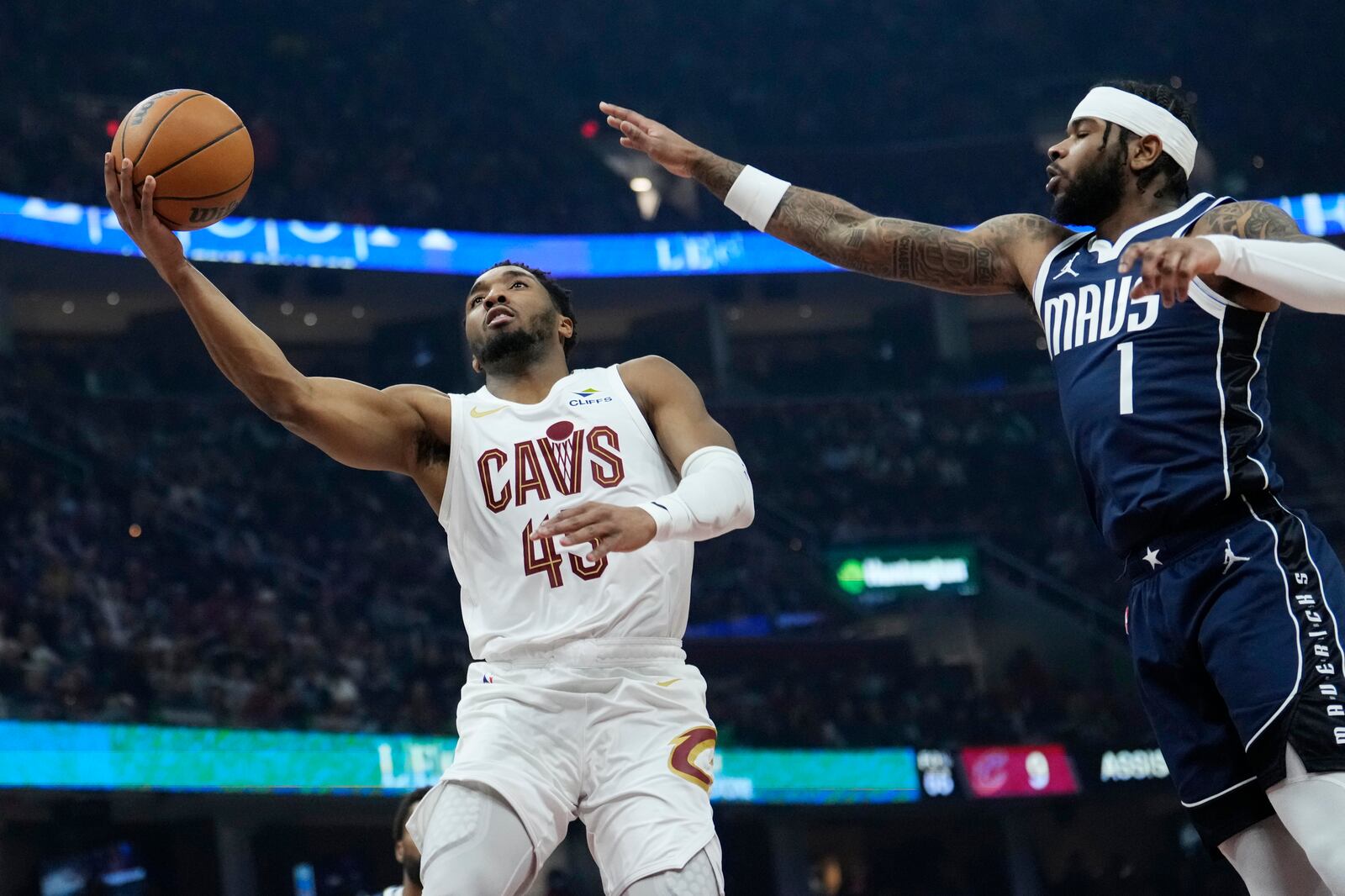 Cleveland Cavaliers guard Donovan Mitchell (45) goes to the basket next to Dallas Mavericks guard Jaden Hardy (1) in the first half of an NBA basketball game, Sunday, Feb. 2, 2025, in Cleveland. (AP Photo/Sue Ogrocki)