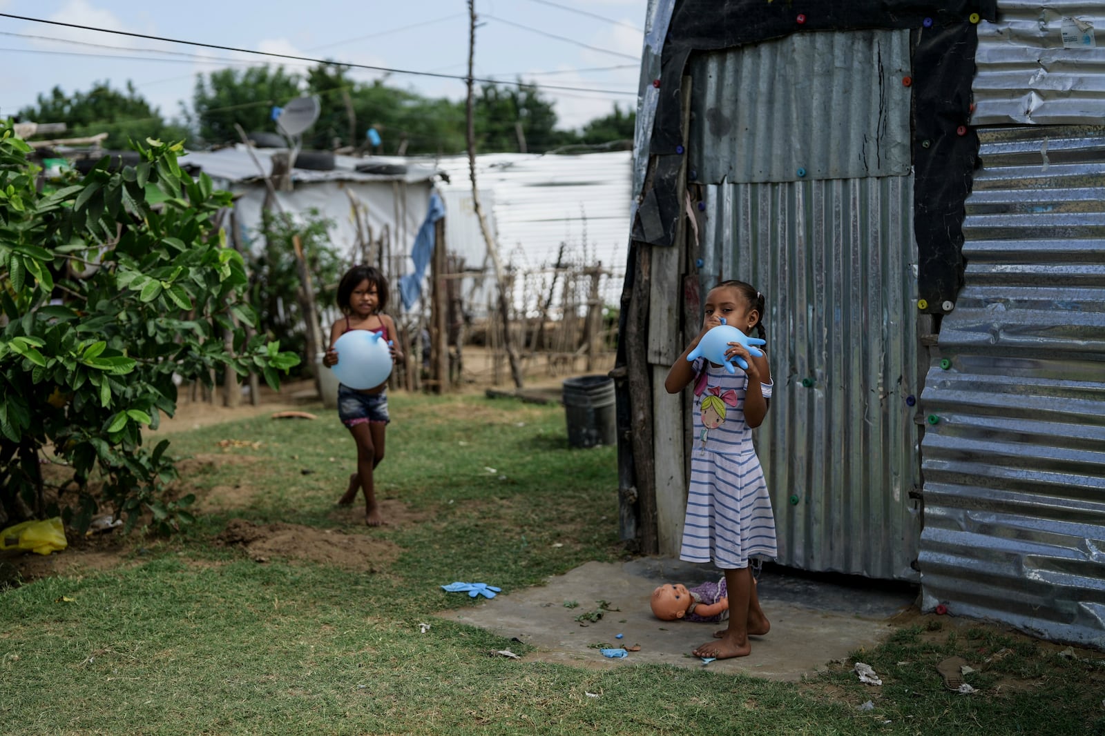 Indigenous girls from the Wayuu community play with rubber gloves in the Somos Unidos neighborhood on the outskirts of Maicao, Colombia, Wednesday, Feb. 5, 2025. (AP Photo/Ivan Valencia)