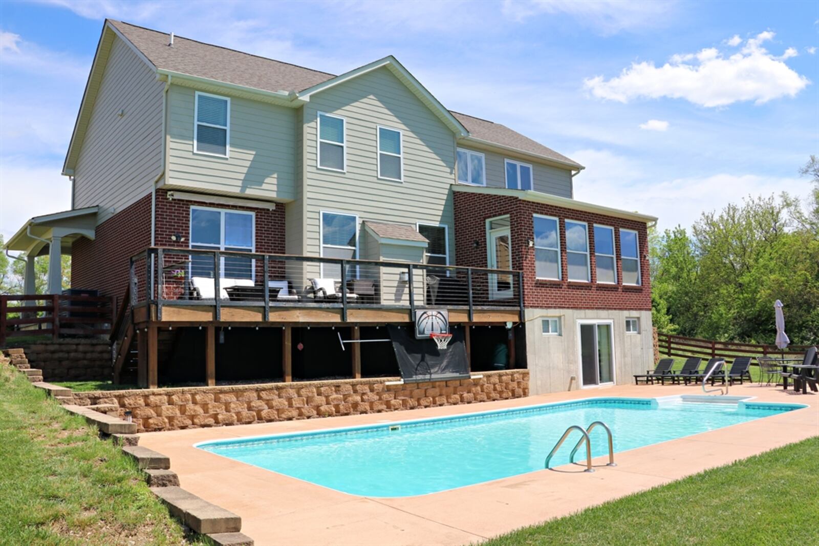 The terraced backyard has a corral fence surrounding the in-ground swimming pool.