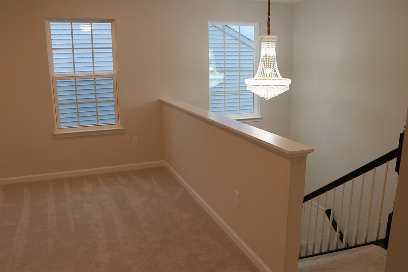 A crystal chandelier hangs above the semi-open staircase, which leads from the great room up to a loft family room.