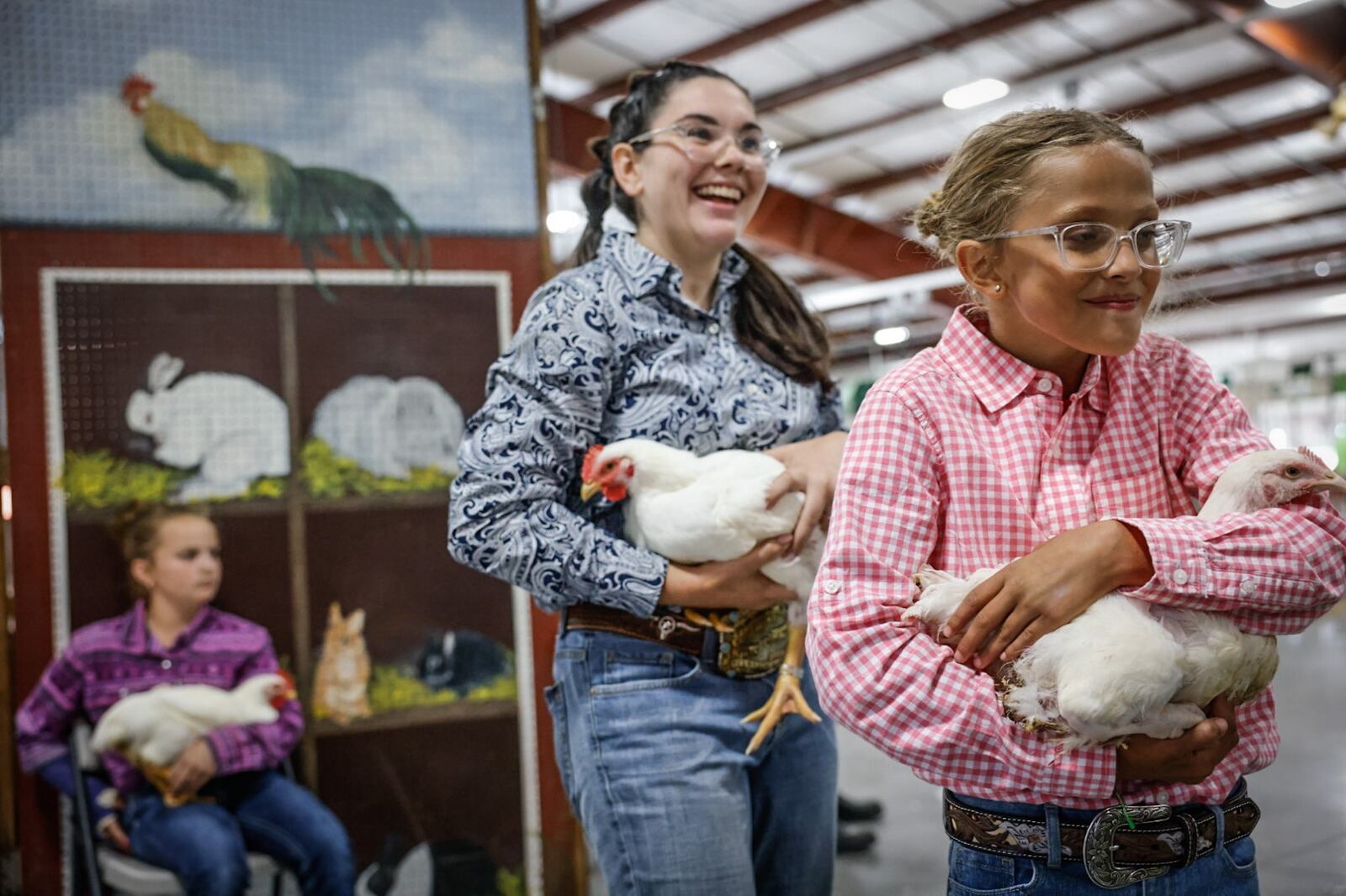 Ashlynn Cummins, left from Germantown and Ell Grace Rike from Lewisburg head to the stage to auction their meat chickens during the Junior fair sale at the Montgomery County Fair Wednesday July 10, 2024. Rike made $150 for her meat chicken. JIM NOELKER/STAFF