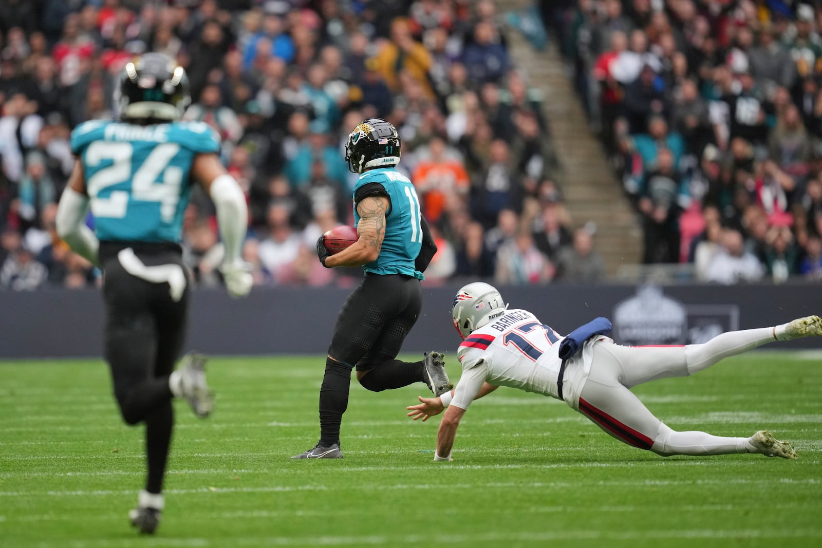 Jacksonville Jaguars' Parker Washington breaks from New England Patriots punter Bryce Baringer (17) to score on a 96-yard punt return during the first half of an NFL football game, Sunday, Oct. 20, 2024, in London. (AP Photo/Kin Cheung)