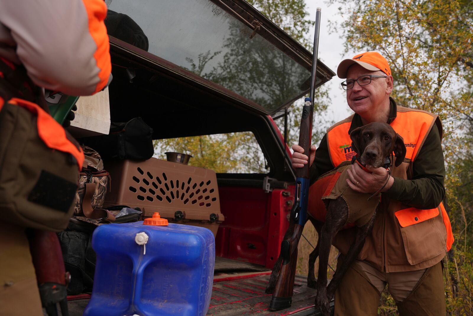 Minnesota Governor and Democratic Vice Presidential candidate Tim Walz holds Matt Kucharski's dog Libby, a 6-year-old German Shorthaired Pointer, to give her a drink during the annual Minnesota Governor's Pheasant Hunting Opener, Saturday, Oct. 12, 2024, near Sleepy Eye, Minn. (Anthony Souffle/Star Tribune via AP)