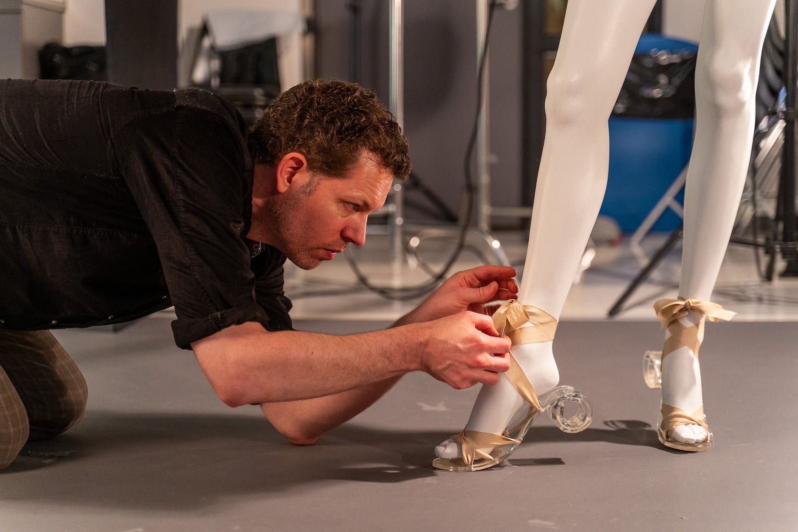 Behind the scenes of "Sporting Fashion" is curator Kevin L. Jones. He is seen here adjusting a sandal ribbon. Contributed photo by Brian Davis, FIDM Museum/Courtesy American Federation of Arts