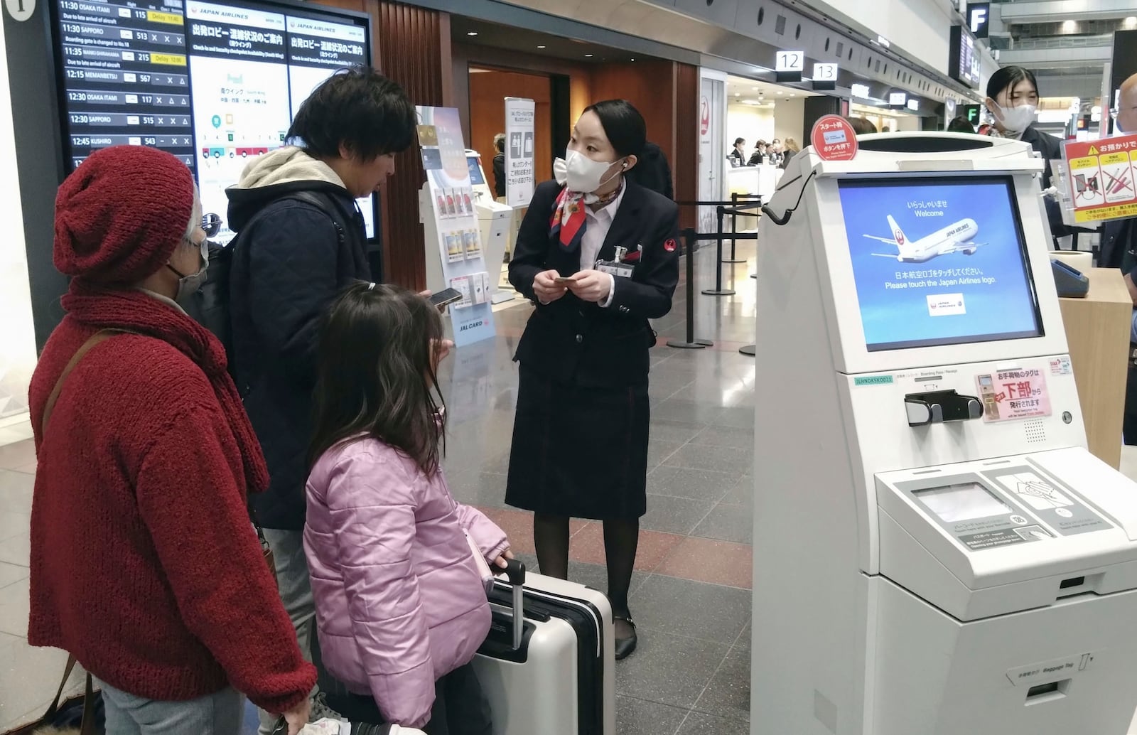 A staff member of Japan Airlines helps customers at the Haneda airport in Tokyo, Thursday, Dec. 26, 2024, after the airlines said it was hit by a cyberattack. (Shingo Fukuma/Kyodo News via AP)