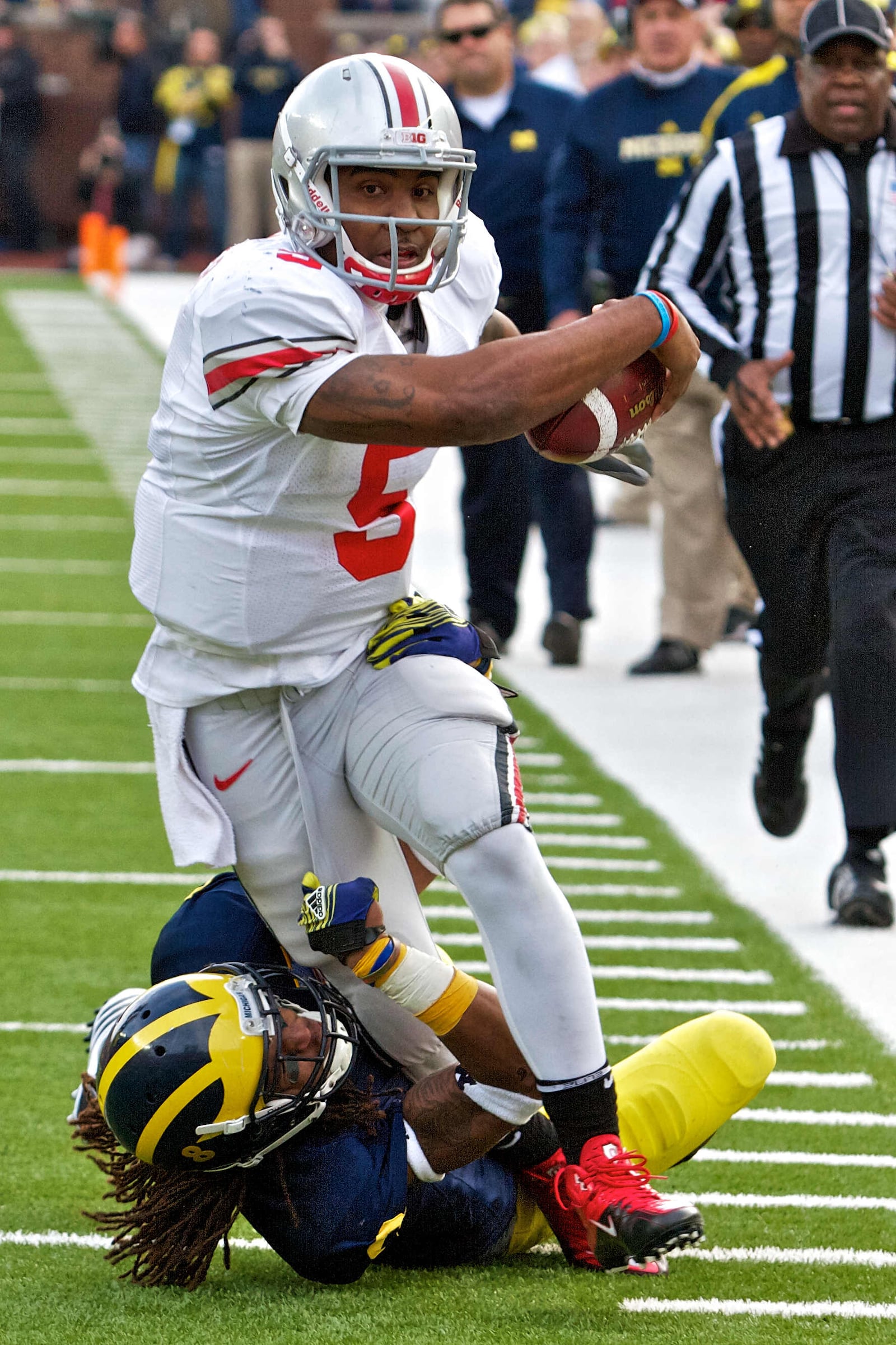 Ohio State Buckeyes quarterback Braxton Miller (5) is tackled by Michigan Wolverines cornerback J.T. Floyd (8) after a run that extended a drive in the third quarter of the game between Ohio State and Michigan at Michigan Stadium, Ann Arbor, Michigan. Michigan defeated Ohio State 40-34.