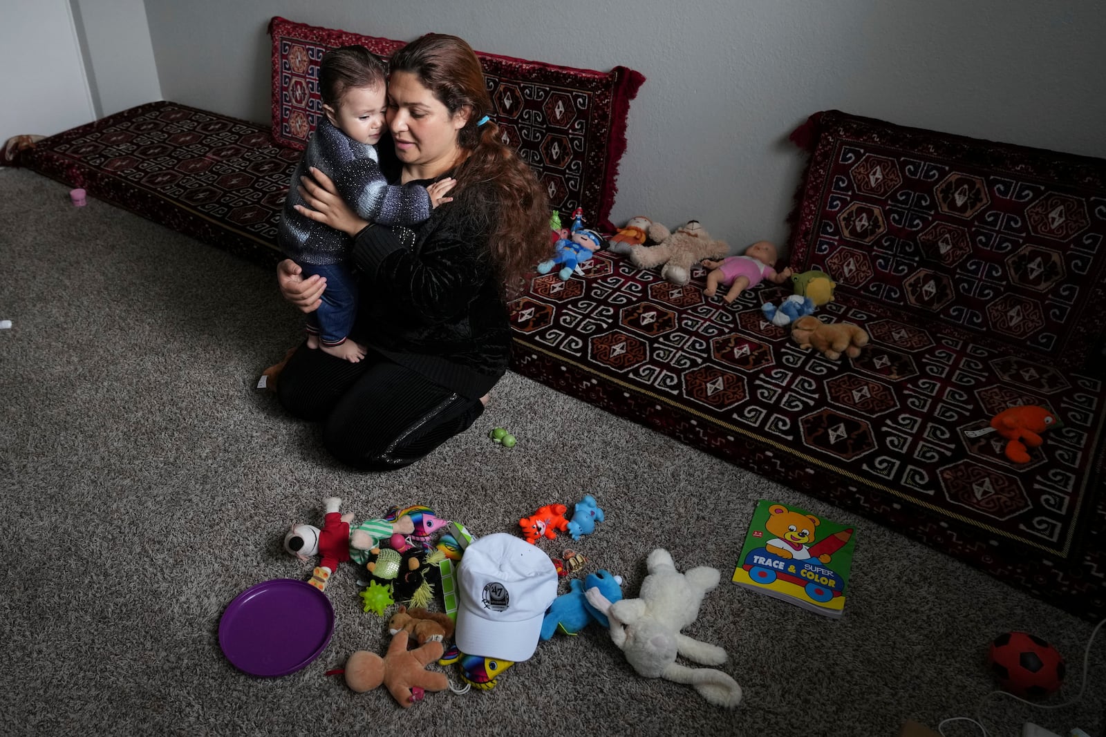 After arriving to the United States from Albania, hours earlier, Noria Sdeqi comforts her tired daughter Sadaf Osmani, 13 months, in their new home in Rancho Cordova, Calif., Wednesday, March 12, 2025. (AP Photo/Rich Pedroncelli)