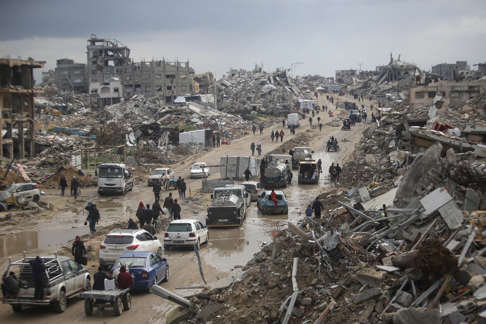 Cars and pedestrians move along a road amid widespread destruction caused by the Israeli military's ground and air offensive against Hamas in Gaza City's Jabaliya refugee camp, Friday, Feb. 7, 2025. (AP Photo/Jehad Alshrafi)