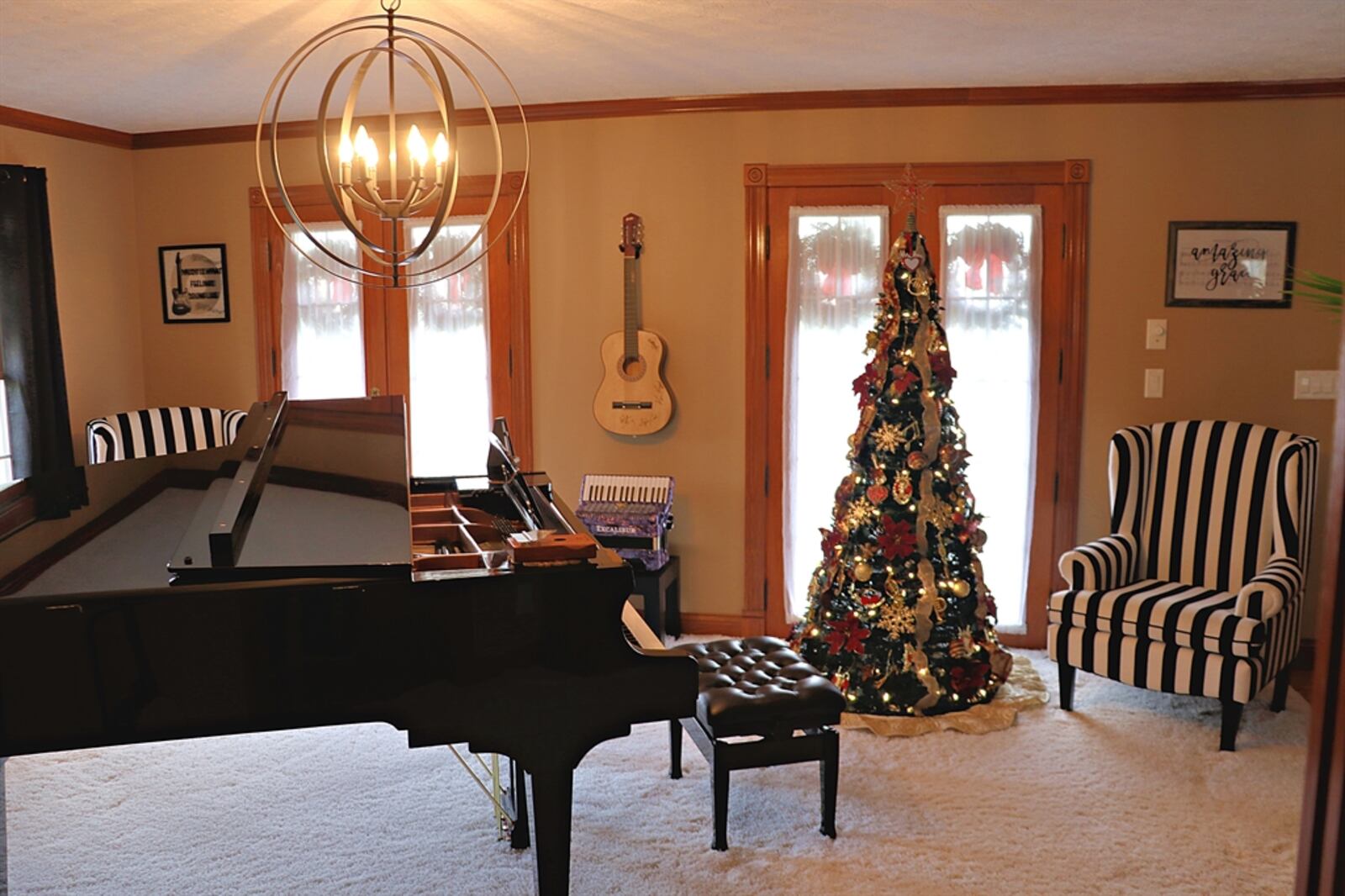 The formal living room is used as a music room. The room has two tall windows with pond views and two sets of French doors. 