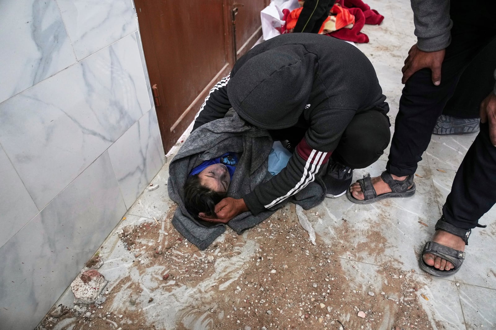 EDS NOTE GRAPHIC CONTENT.- A man grieves as he looks at the body of a child killed in an Israeli army airstrike, before the child is prepared for burial in Khan Younis, southern Gaza Strip, Thursday, March 20, 2025. (AP Photo/Abdel Kareem Hana)