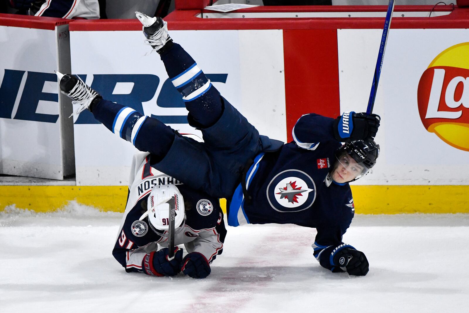 Columbus Blue Jackets' Kent Johnson (91) trips up Winnipeg Jets' Vladislav Namestnikov (7 during the third period of an NHL hockey game in Winnipeg, Manitoba, Sunday, Dec. 8, 2024. (Fred Greenslade/The Canadian Press via AP)