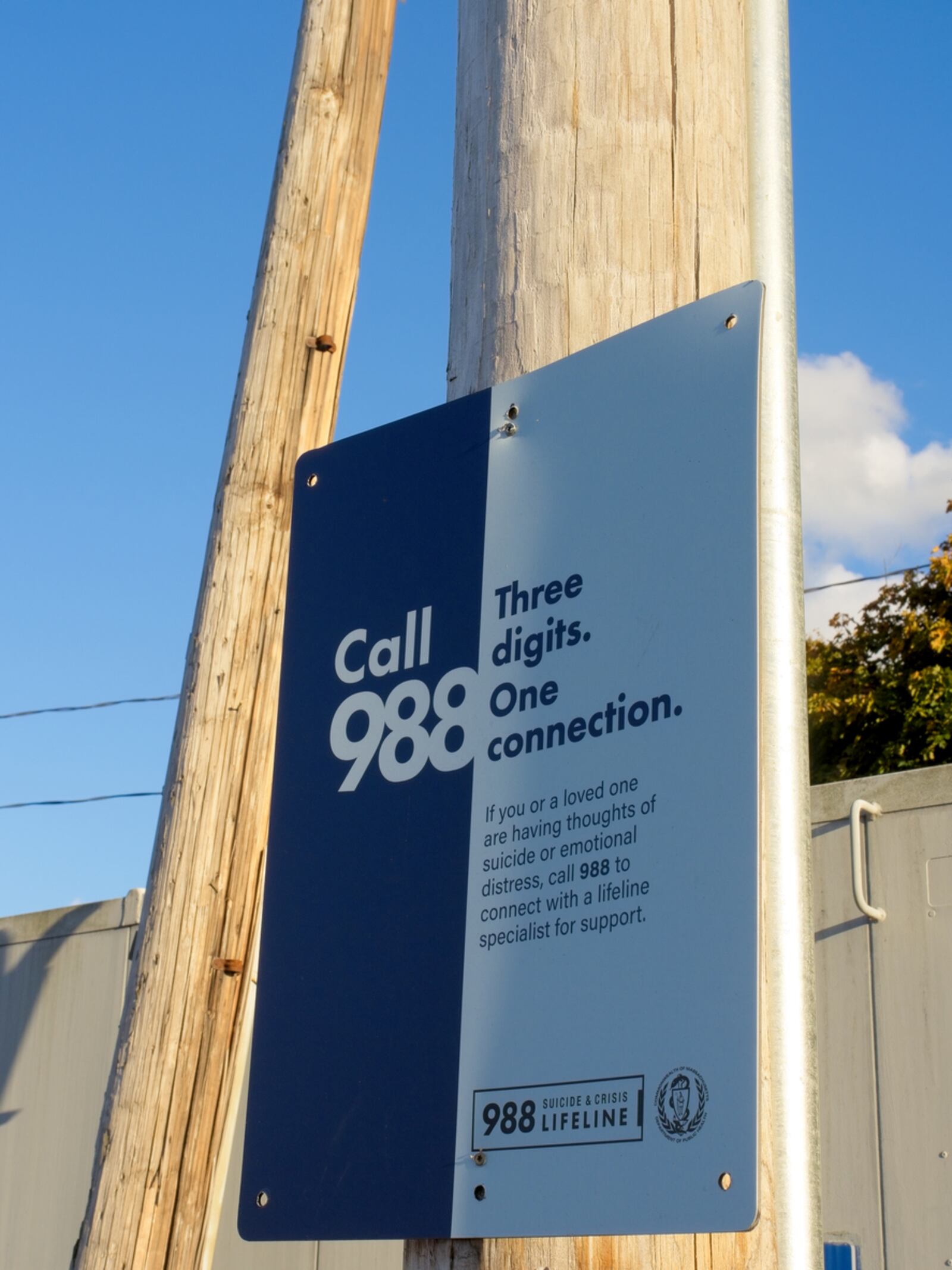 A suicide prevention sign is seen on pole along commuter train crossing. The 988 hotline was launched by the U.S. government for anyone who needs mental health support or is considering suicide. iSTOCK/COX