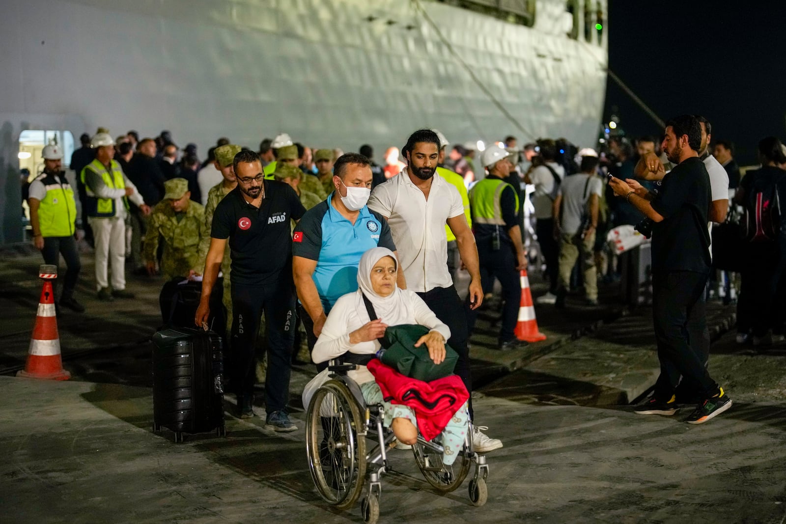 People, mostly Turkish nationals, disembark from Turkish TCG Sancaktar military ship after being evacuated from Lebanon's capital Beirut to Turkey, in Mersin port, southern Turkey, early Friday, Oct. 11, 2024. (AP Photo/Emrah Gurel)