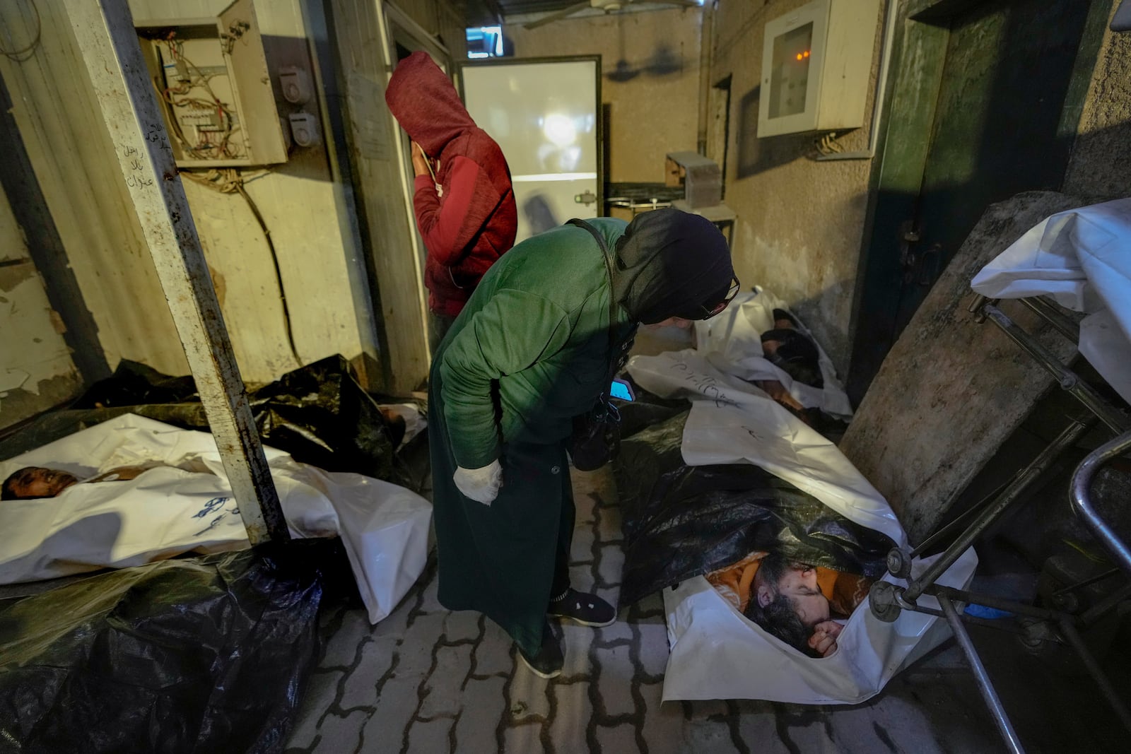 EDS NOTE: GRAPHIC CONTENT - Syrians examine bodies wrapped in plastic bags while searching for missing people at the morgue of Al-Mojtahed hospital in Damascus, Syria, on Wednesday, Dec. 11, 2024. Many are flocking to morgues, hoping to identify loved ones who have been killed or were imprisoned under the rule of President Bashar Assad, whose government collapsed over the weekend. (AP Photo/Hussein Malla)