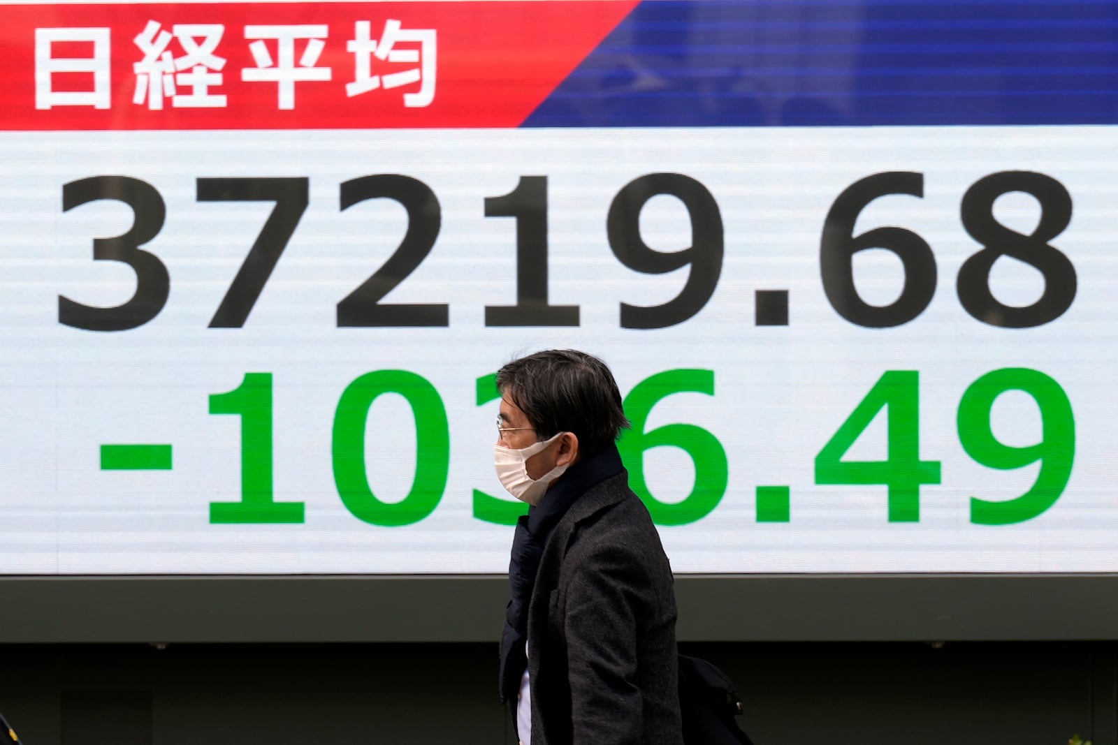 A person walks in front of an electronic stock board showing Japan's Nikkei index at a securities firm Friday, Feb. 28, 2025, in Tokyo. (AP Photo/Eugene Hoshiko)