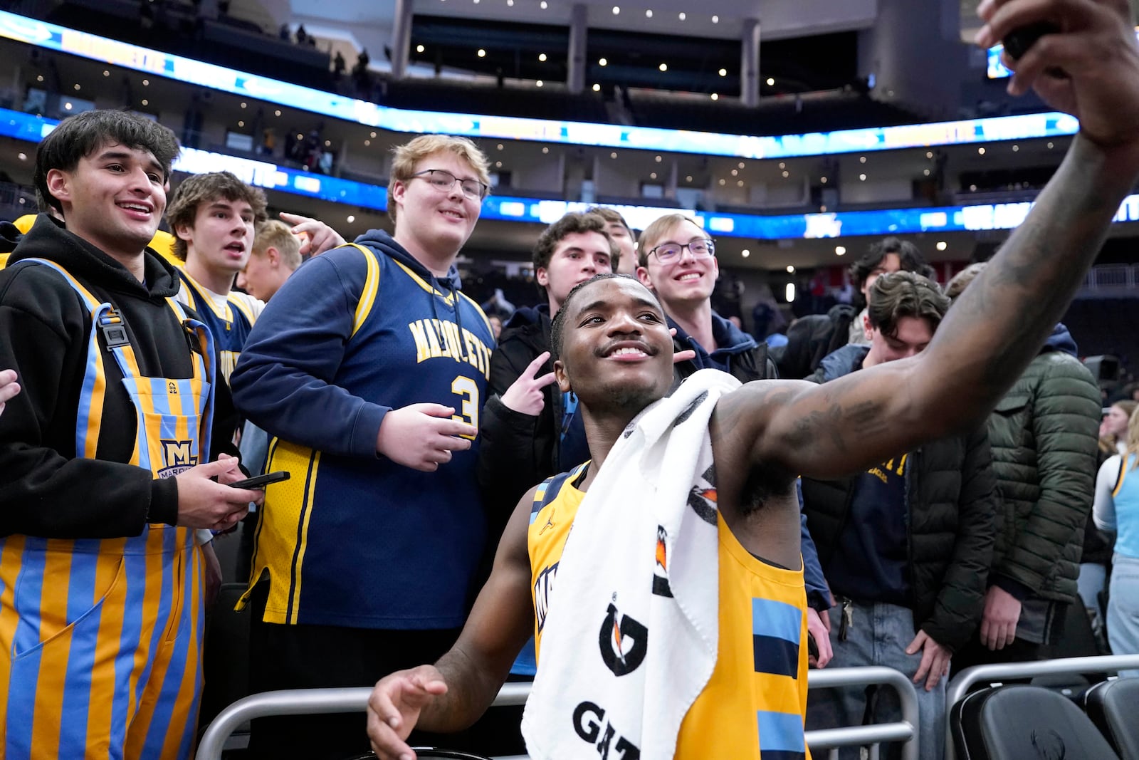 Marquette guard Kam Jones (1) takes selfies with the student section after defeating Wisconsin in an NCAA college basketball game Saturday, Dec. 7, 2024, in Milwaukee, Wis. (AP Photo/Kayla Wolf)