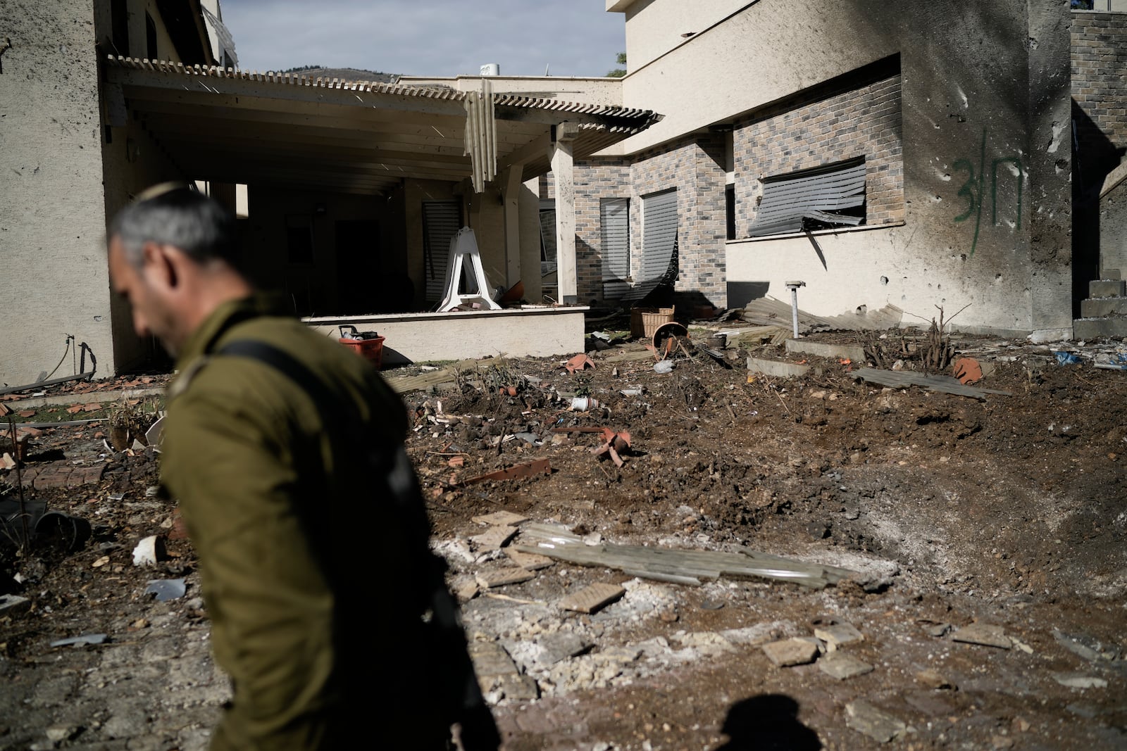 An Israeli soldier inspects the site where a rocket fired from Lebanon landed in a backyard in Kiryat Shmona, northern Israel, Tuesday Nov. 26, 2024. (AP Photo/Leo Correa)