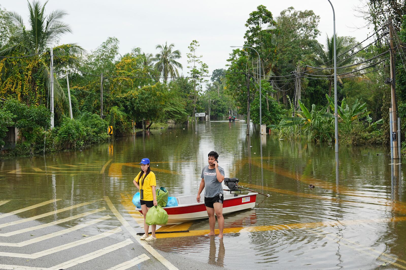 People use a boat to cross a flooded area in Tumpat, outskirts of Kota Bahru in Kelantan state on the east coast of Malaysia, Tuesday, Dec. 3, 2024. (AP Photo/Vincent Thian)