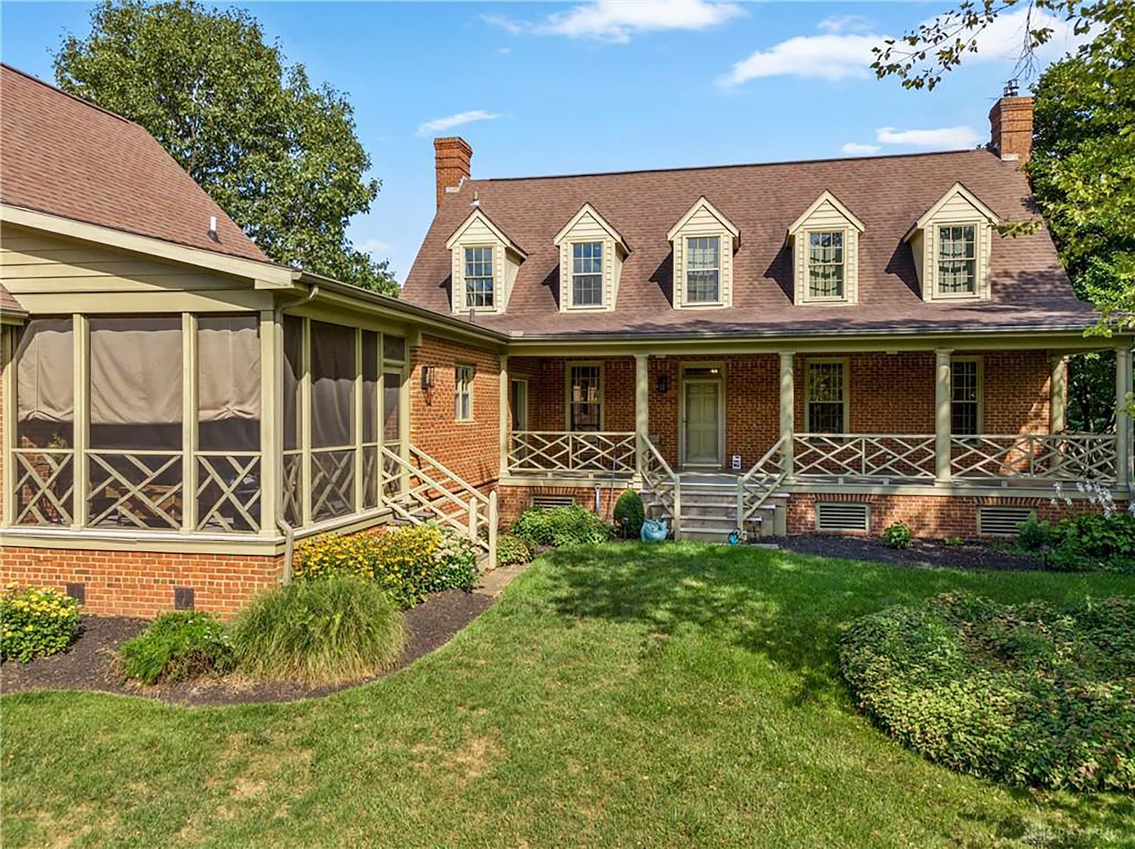 The rear of the home has dormers, covered porch and covered screen in porch, both with steps leading to the yard.