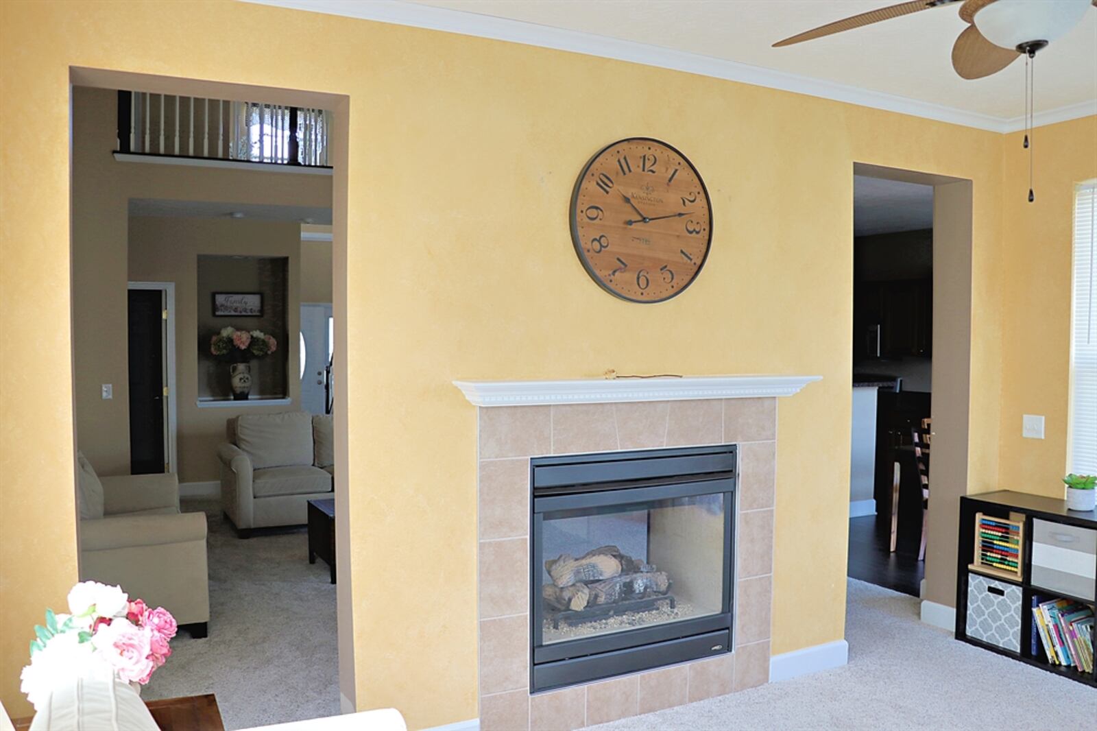 The dual-sided gas fireplace has a wood mantel and is flanked by two thresholds into a sunroom.