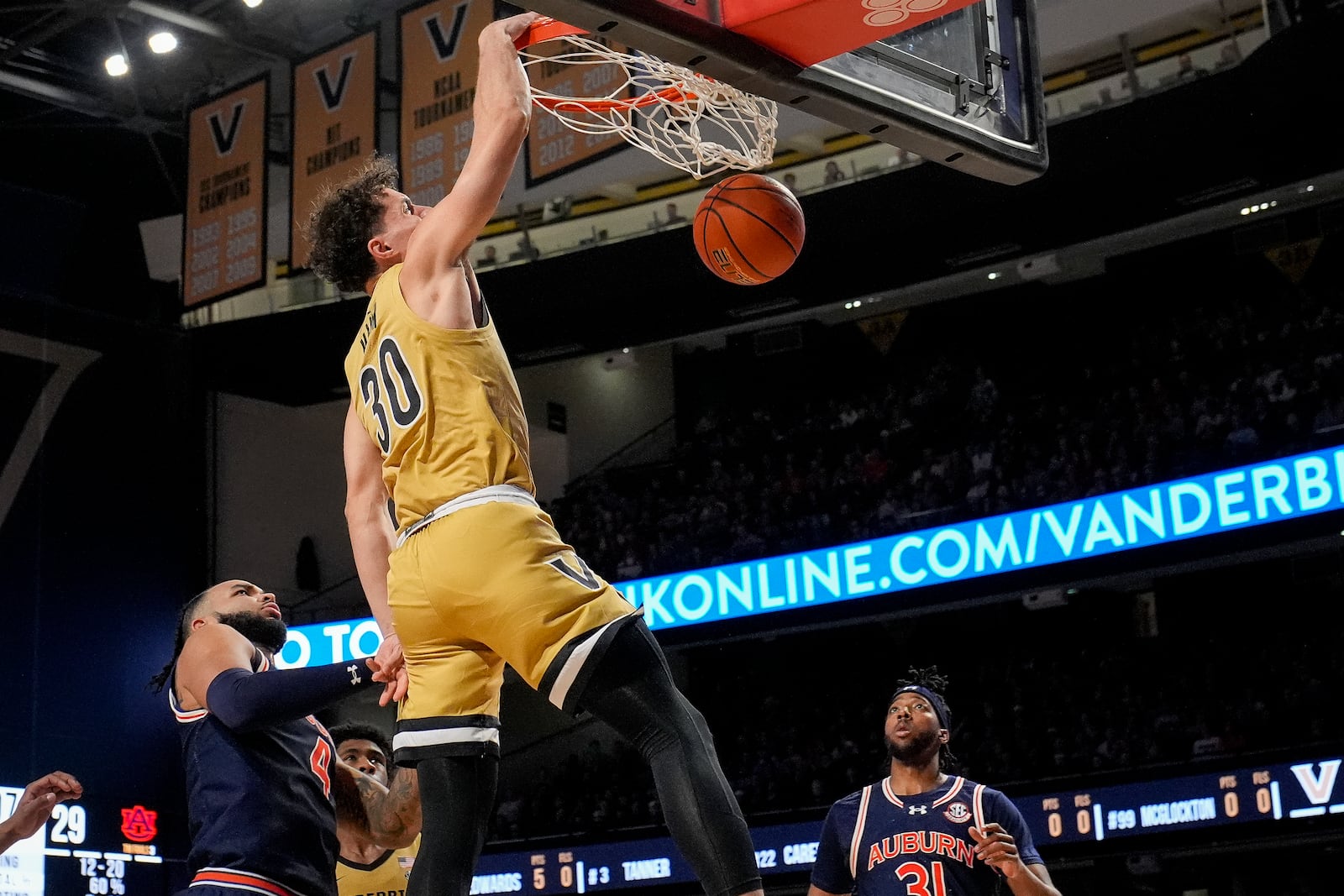 Vanderbilt guard Chris Manon (30) dunks the ball over Auburn forwards Johni Broome, left and Chaney Johnson, right, during the first half of an NCAA college basketball game Tuesday, Feb. 11, 2025, in Nashville, Tenn. (AP Photo/George Walker IV)