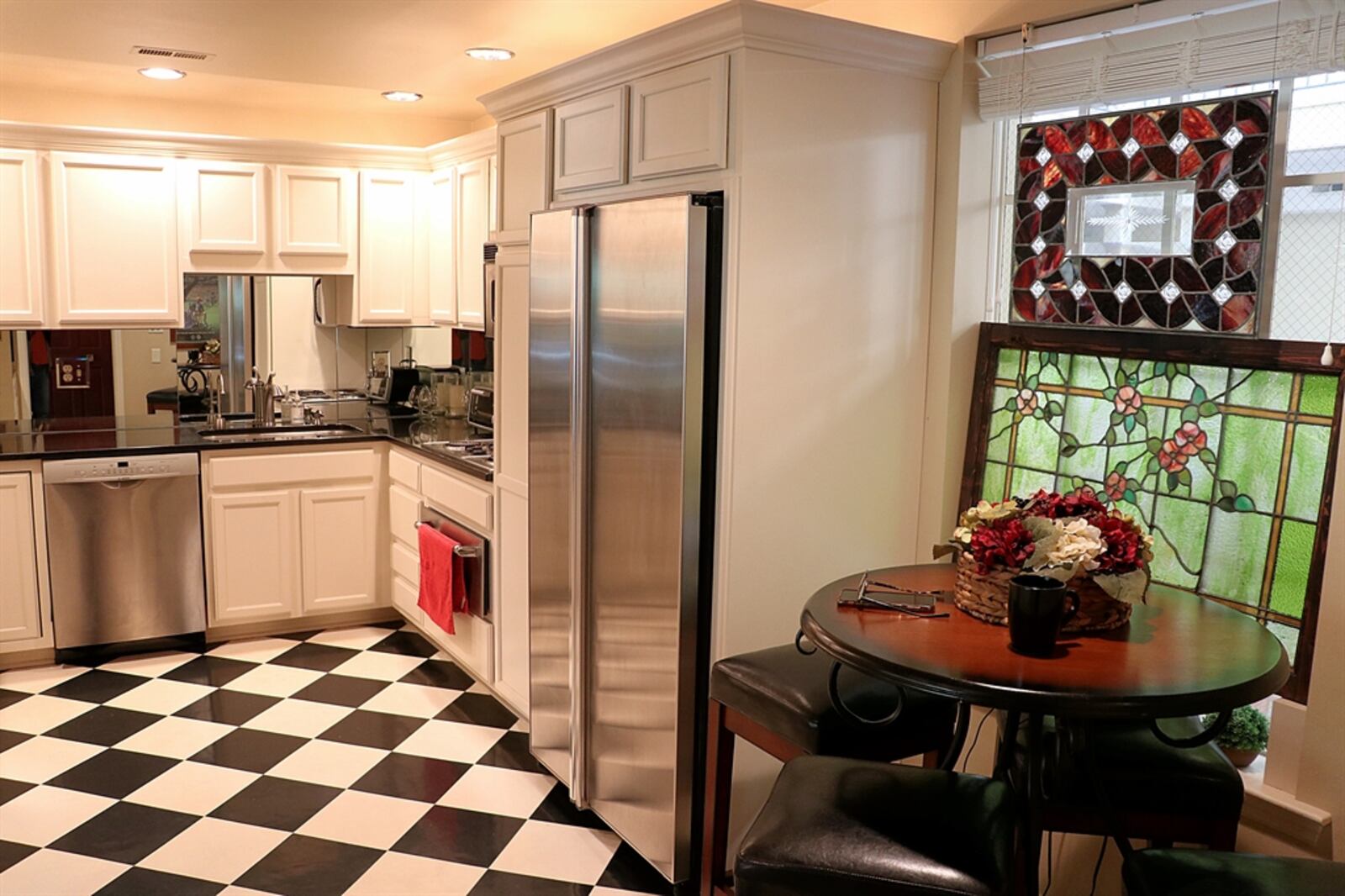 The kitchen has antique white cabinetry with dark granite counters. Stainless-steel appliances include an electric cooktop, wall ovens, dishwasher and refrigerator. 