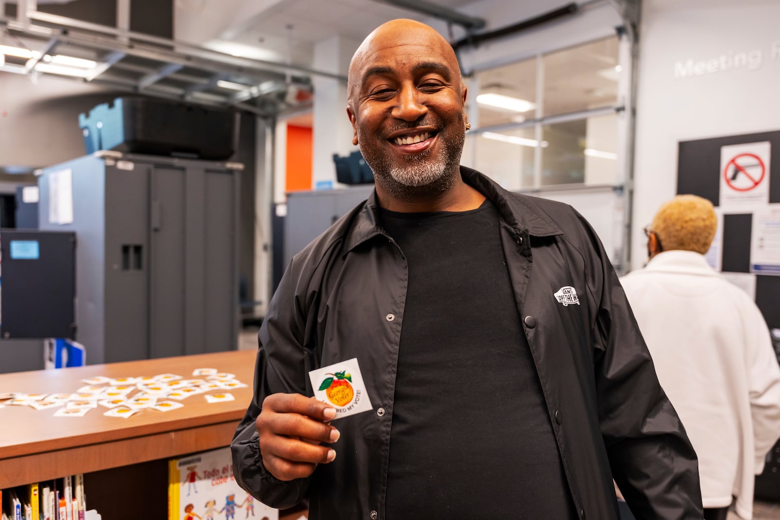 A man holds up his sticker that signifies that he has officially voted in the state of Georgia, Thursday, Oct. 31, 2024, in Atlanta. (AP Photo/Jason Allen)