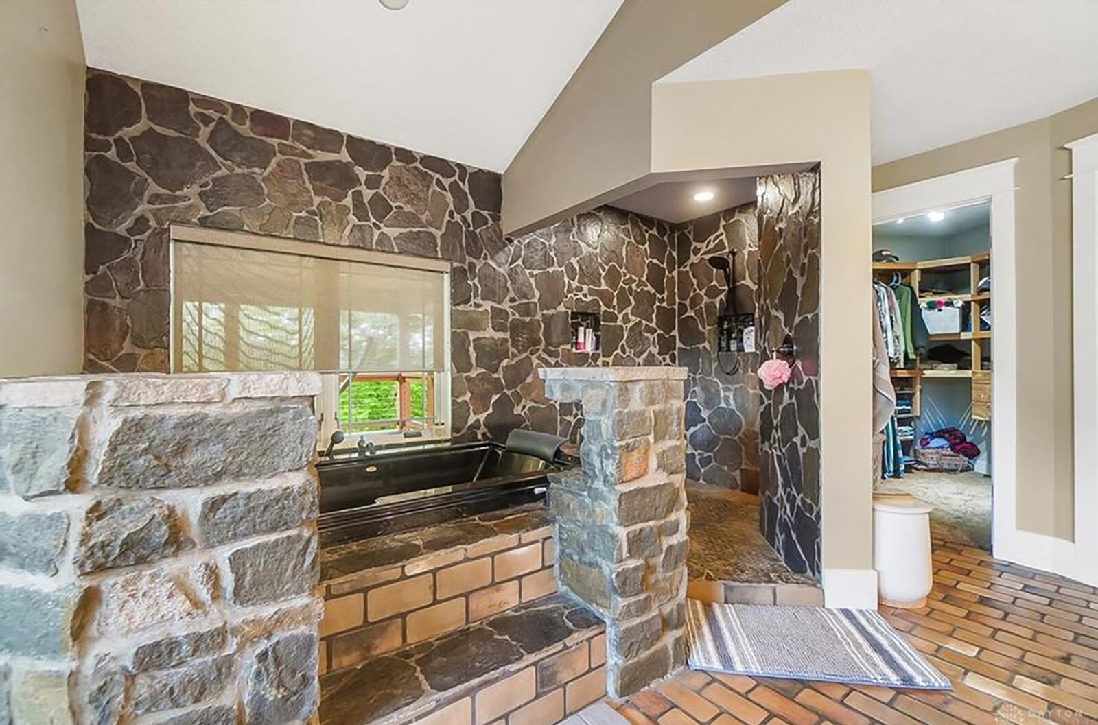 The primary bedroom ensuite bath has slate and stone accents, a jacuzzi tub with stone pillars with lighting and a walk in shower.