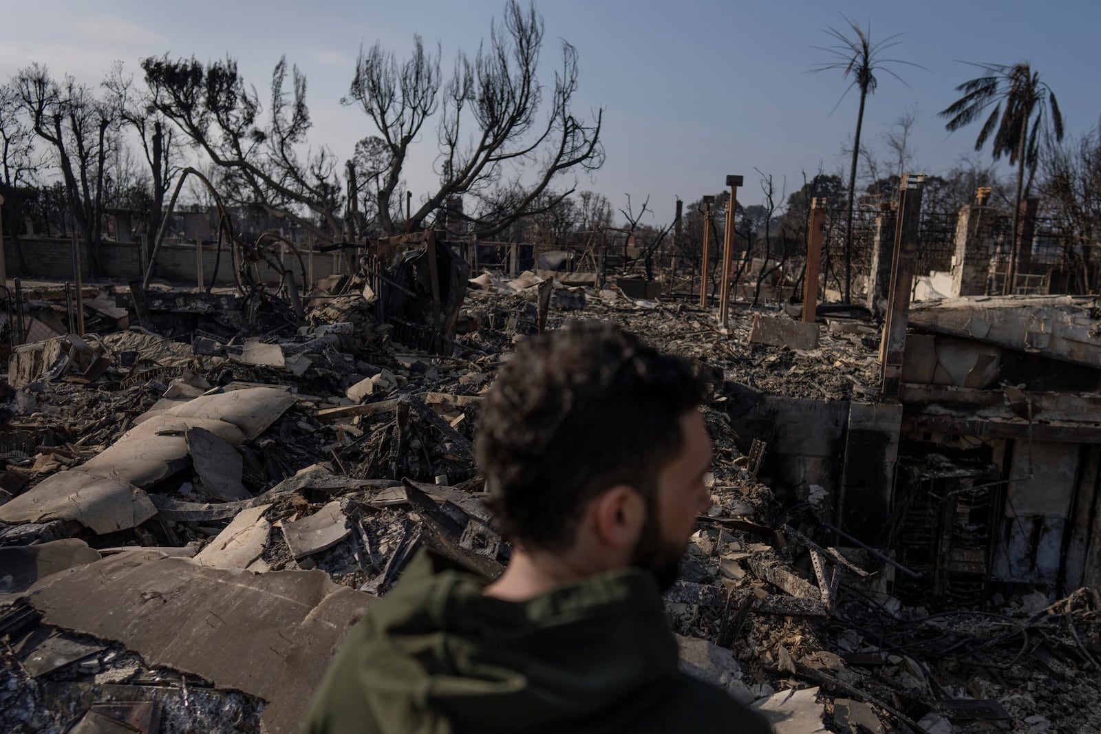 World Central Kitchen Chef Corp member Daniel Shemtob looks out over what remains of his home destroyed by the Palisades Fire, Sunday, Jan. 19, 2025, in Pacific Palisades, Calif. (AP Photo/Carolyn Kaster)