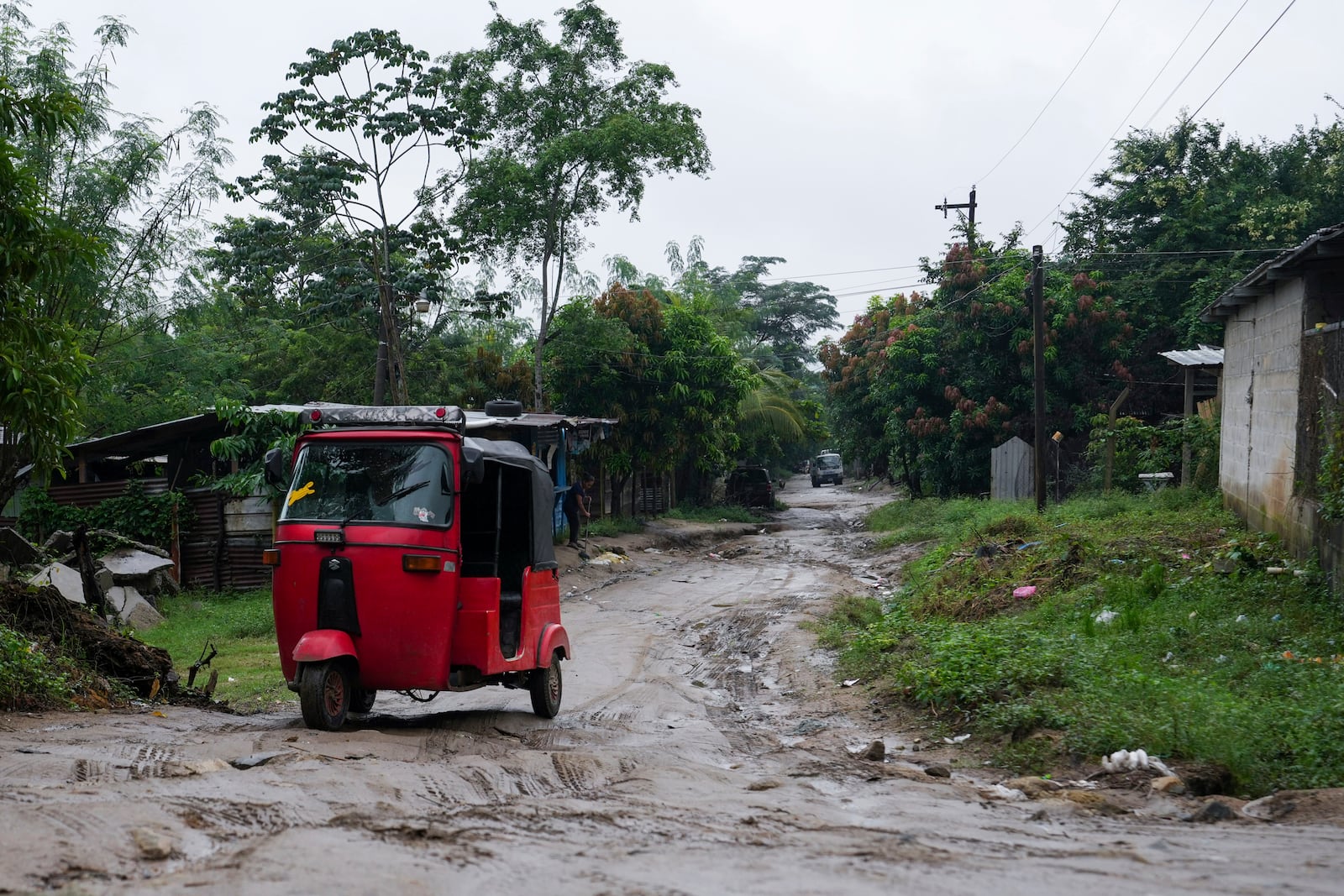 A three-wheeled motorized taxi drives along a dirt road on the outskirts of San Pedro Sula, Honduras, Monday, Dec. 9, 2024. (AP Photo/Moises Castillo)