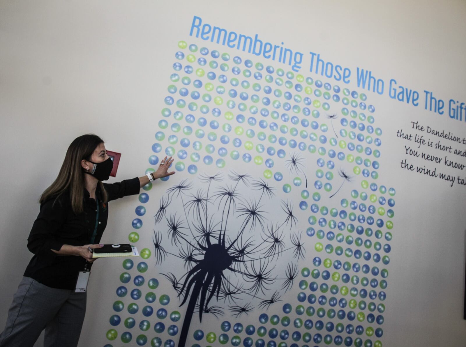 Shannon Price-Schweitzer, executive director of Lions Eye Bank in Moraine, stands by a wall with all of the local donors of ocular tissue. JIM NOELKER/STAFF