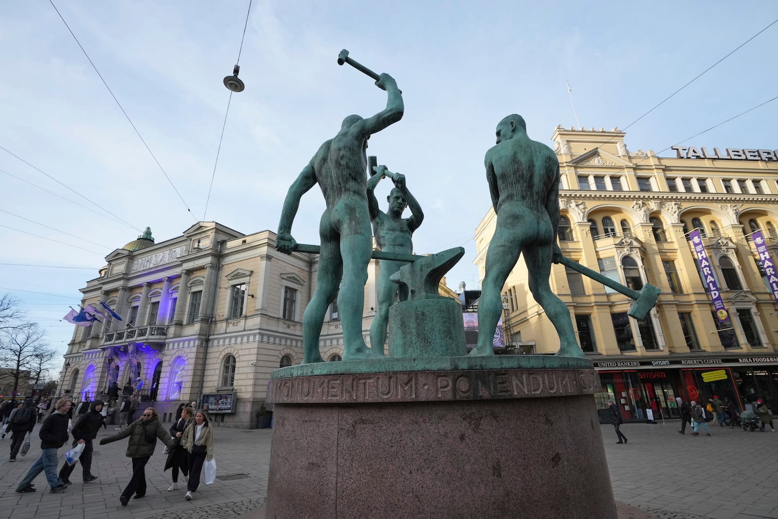 People walk by the Three Smiths statue in the center of Helsinki, Finland, Saturday, March 15, 2025. (AP Photo/Sergei Grits)