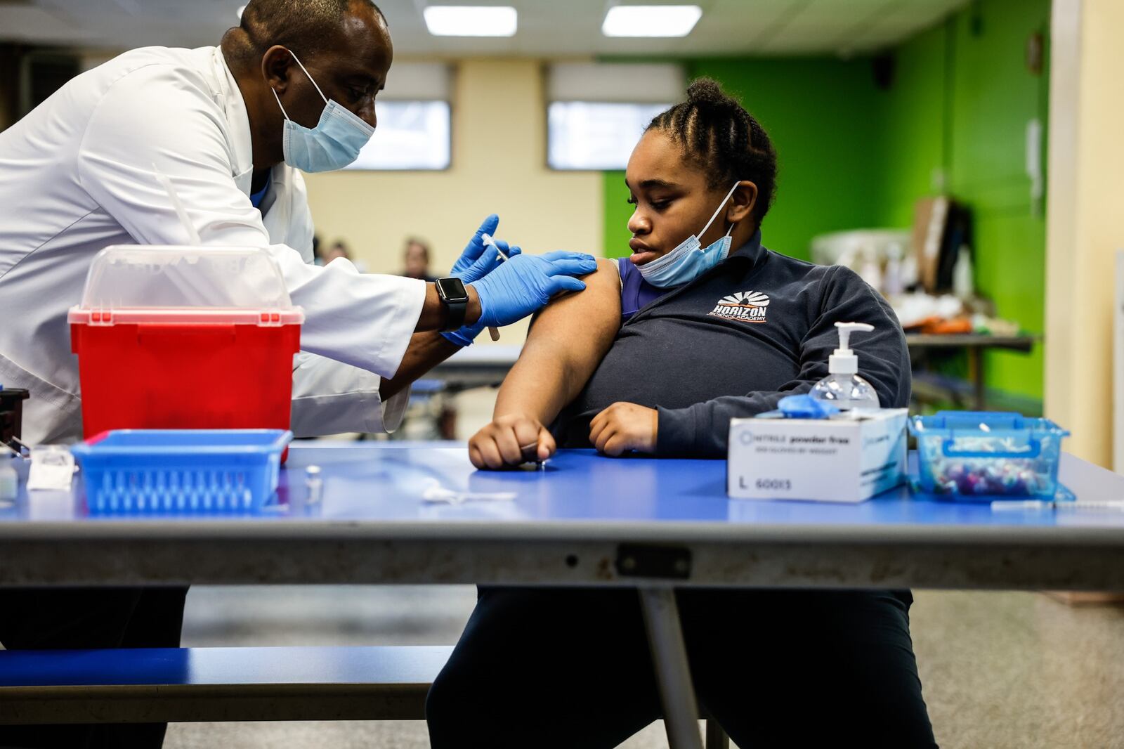 Anthony Watson, R.N.. administers a COVID-19 vaccine to Acani Peterson at Horizon Science Academy Friday March 11, 2022. JIM NOELKER/STAFF