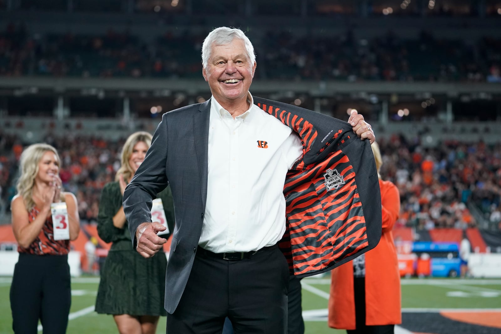 Former Cincinnati Bengals' Ken Anderson holds open his jacket during a "Ring of Honor" ceremony during an NFL football game between the Cincinnati Bengals and the Jacksonville Jaguars, Thursday, Sept. 30, 2021, in Cincinnati. (AP Photo/Michael Conroy)