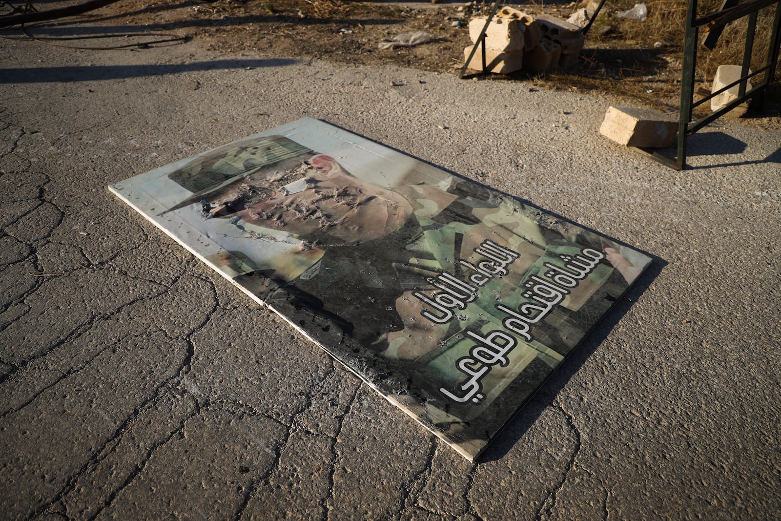 A defaced portrait of Syrian President Bashar Assad lies on the ground in the town of Maarat al-Numan, southwest from Aleppo, Syria, Saturday Nov. 30, 2024. Thousands of Syrian insurgents have fanned out inside Syria's largest city Aleppo and large areas around previously controlled by the government with little resistance from troops.(AP Photo/Omar Albam)